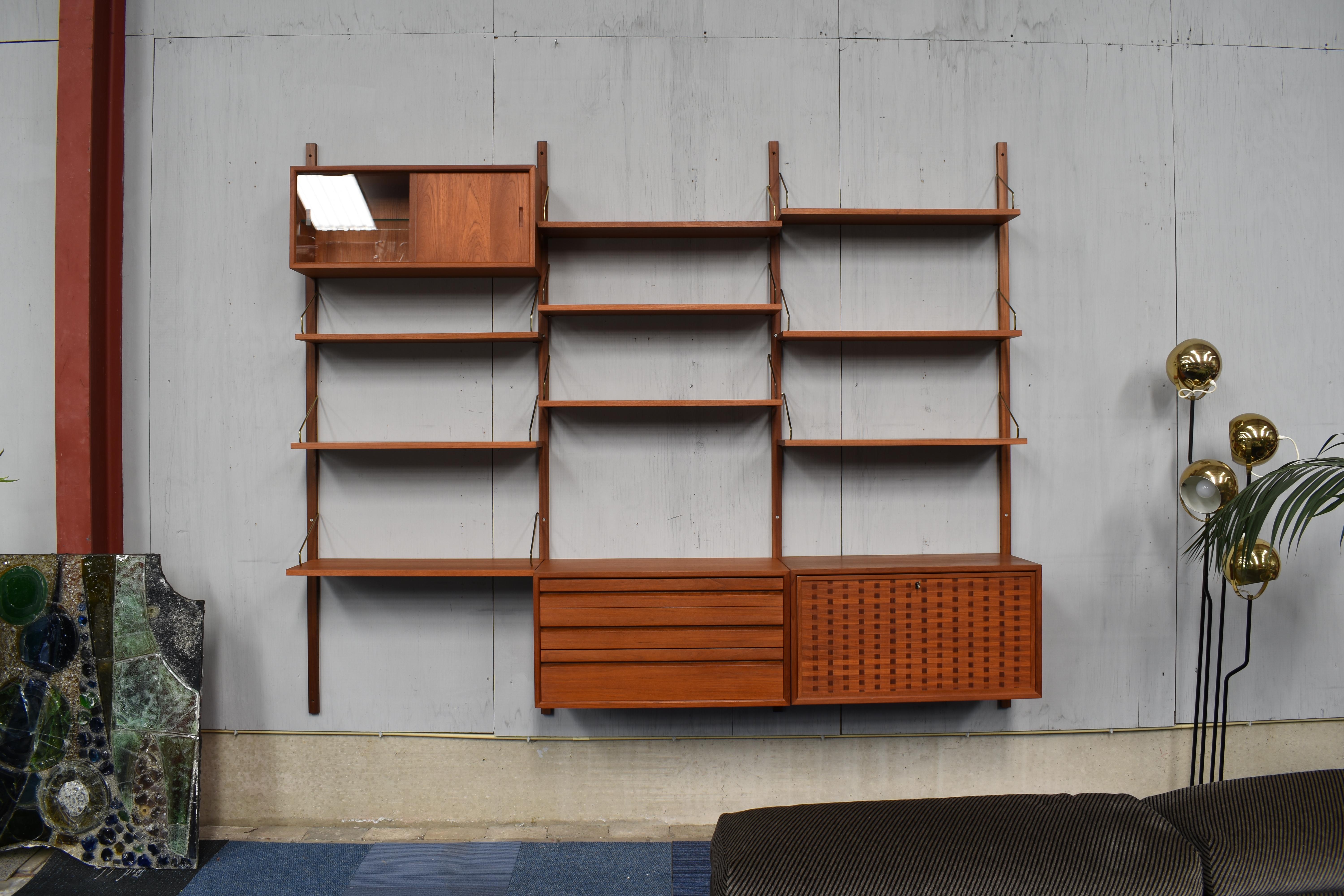 Exclusive edition wall unit by Poul Cadovius in teak and brass. This is an exclusive edition because of the solid brass hinges and solid teak wall mounts. Normally the hinges are made of black lacquered metal and stained beech wood wall mounts. The