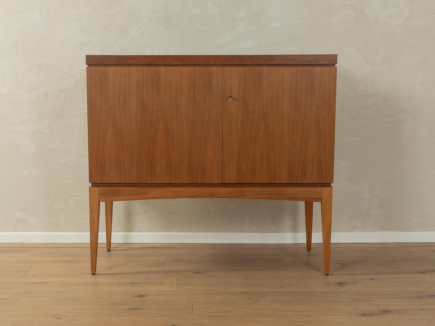 Exklusive Hausbar aus den 1960er Jahren. Hochwertiger nussbaumfurnierter Korpus mit einer Tür, zwei Einlegeböden, zwölf Flaschenhaltern, original grauer Formica-Beschichtung und geraden Beinen. Die Tischplatte kann um 90° gedreht werden und hat