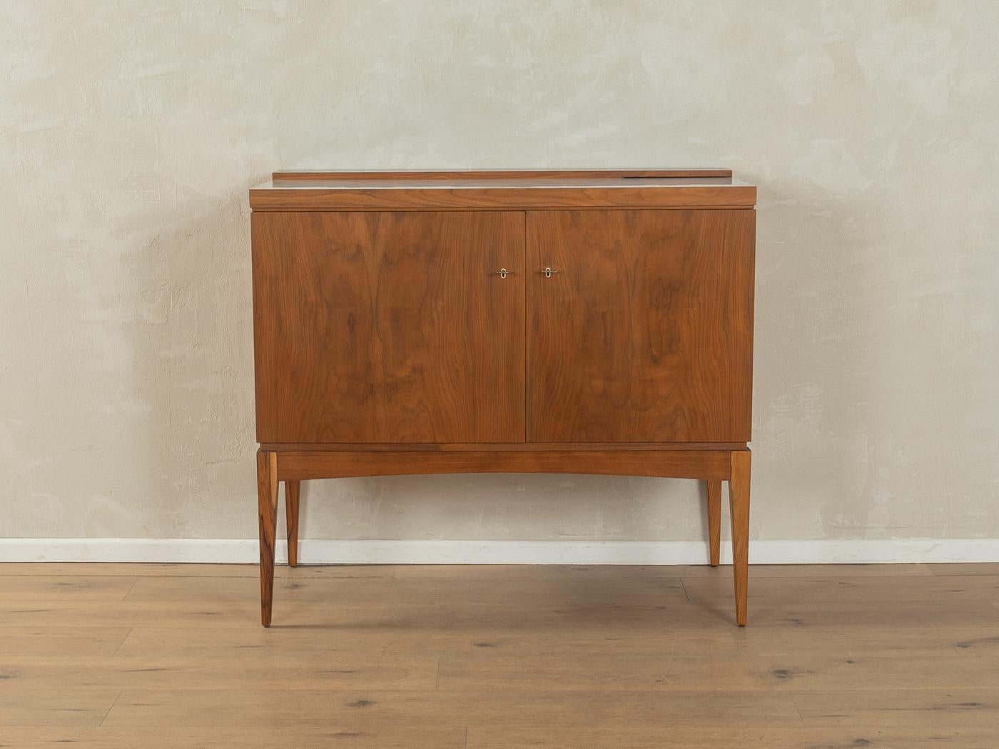 Exclusive home bar from the 1960s. High-quality corpus in walnut veneer with two doors, one shelf, one drawer, original Formica coating in grey and black and straight feet. The table top can opened by 90° and has a foldable leg.

- Very good
