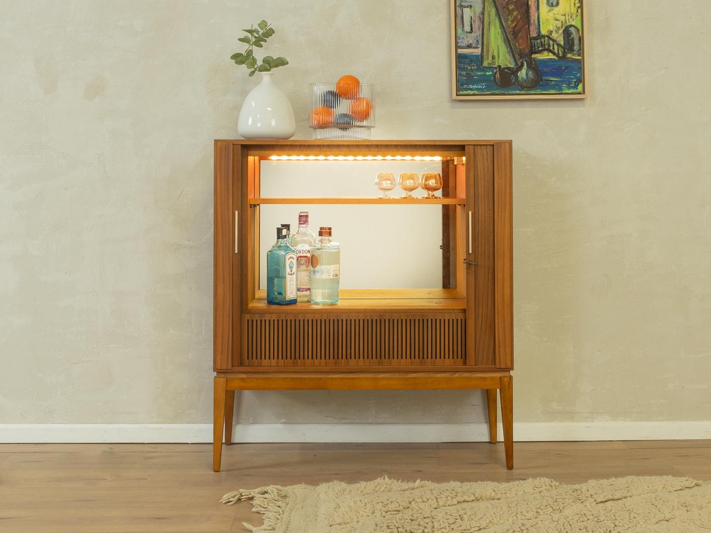 Mobile bar (ex mobile TV) unico nel suo genere, risalente agli anni '60. Corpo di alta qualità in impiallacciato di noce con due ante a tamburo, un ripiano, un vano bar illuminato con specchio e piedi affusolati.

Caratteristiche di qualità:
ottima