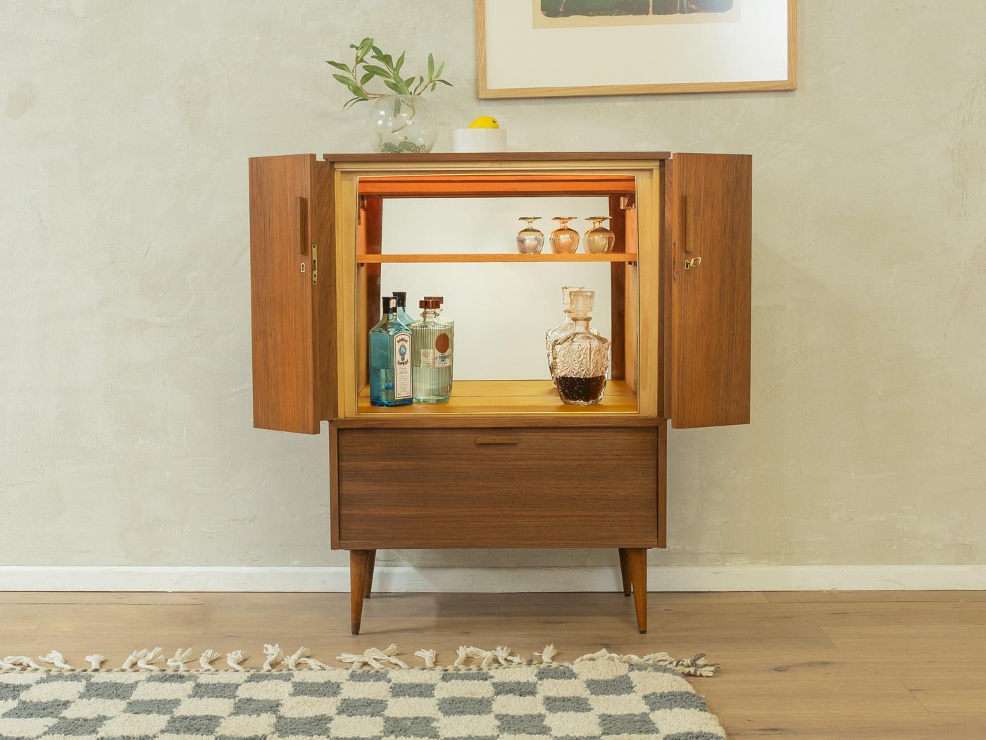Mobile bar unico (ex mobile TV di Grundig) degli anni '60. Corpo di alta qualità in impiallacciatura di noce con due ante pieghevoli, un ripiano, un vano bar illuminato con specchio, un'anta a battente, un cassetto e piedi