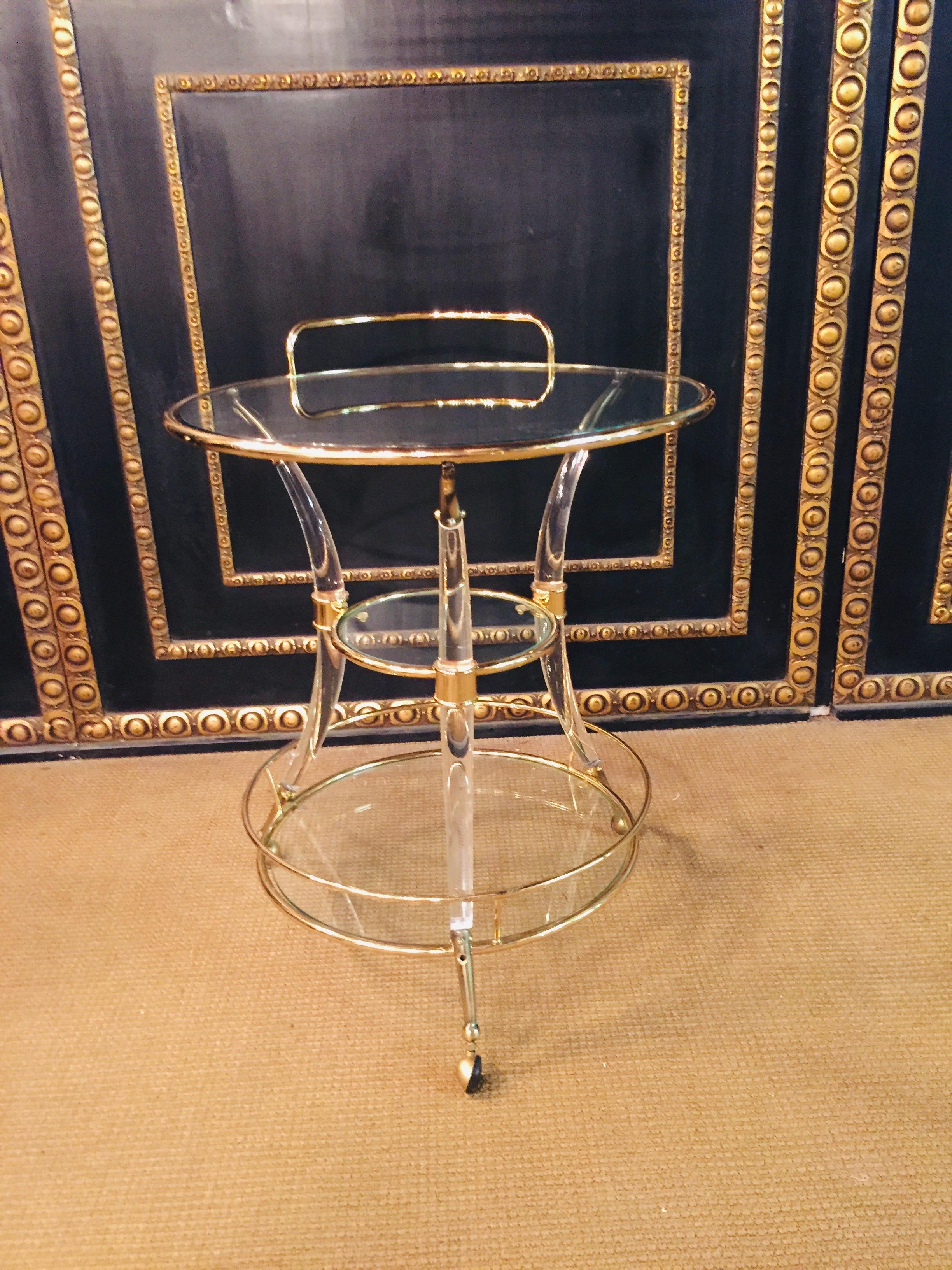 Round tea table with 3-glass plates with 3-curved acrylic legs ending in brass rolls.
With handle to push.