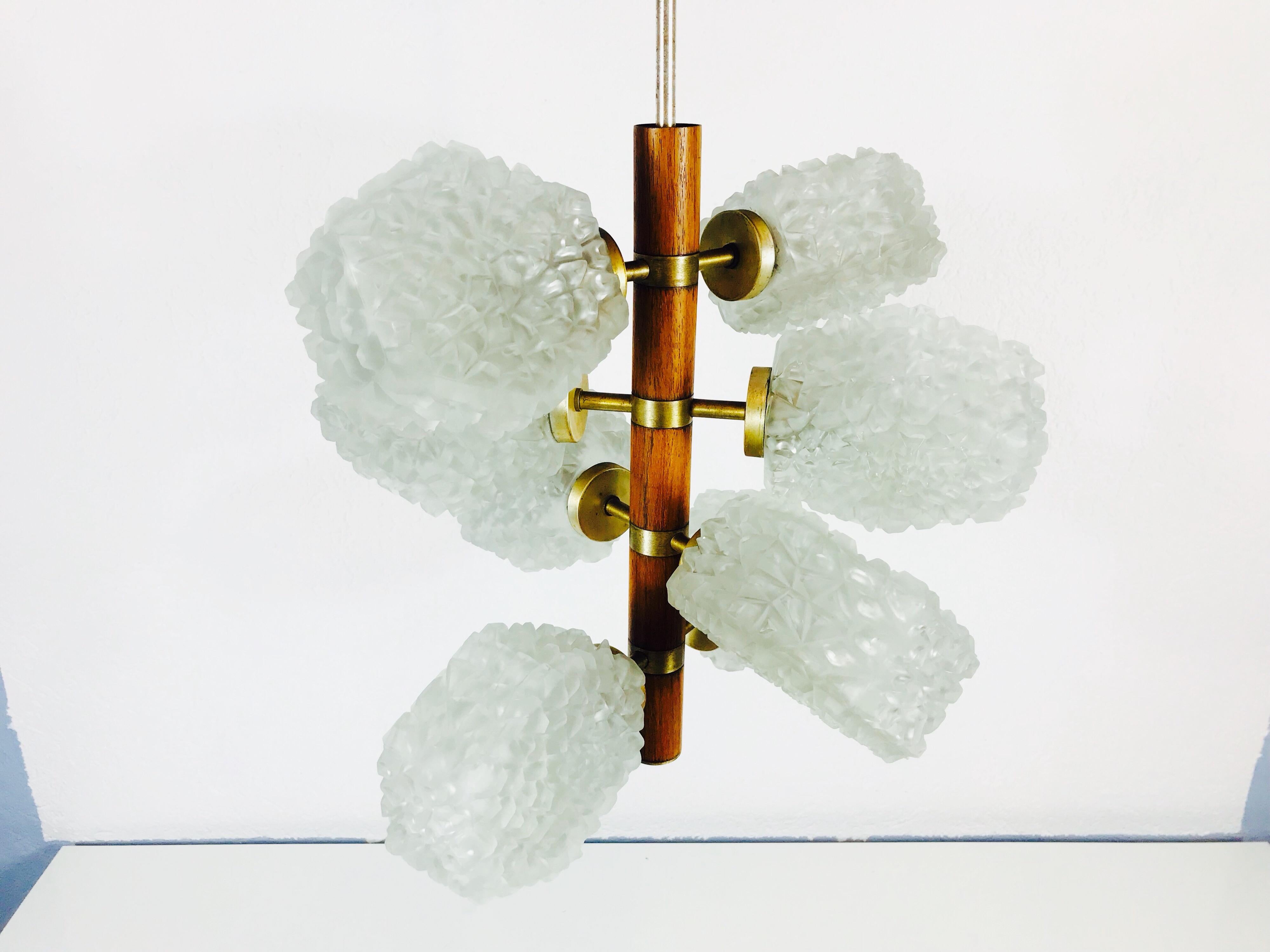 Temde teak and brass adjustable chandelier made in Germany in the 1960s. It is fascinating with its rare glass shapes. The eight arms are all adjustable and are made of polished brass. The long bar above the lamp is also brass