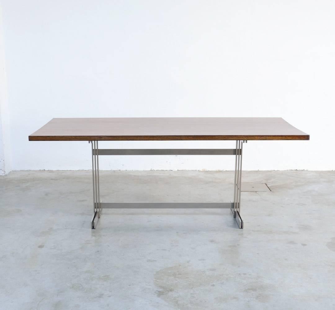 Cette table à manger exclusive a été conçue par Jules Wabbes pour le Mobilier Universel en 1959.
Le plateau rectangulaire est réalisé en bandes massives de wengé et repose sur une base en acier.
Ce meuble de haute qualité est en très bon état