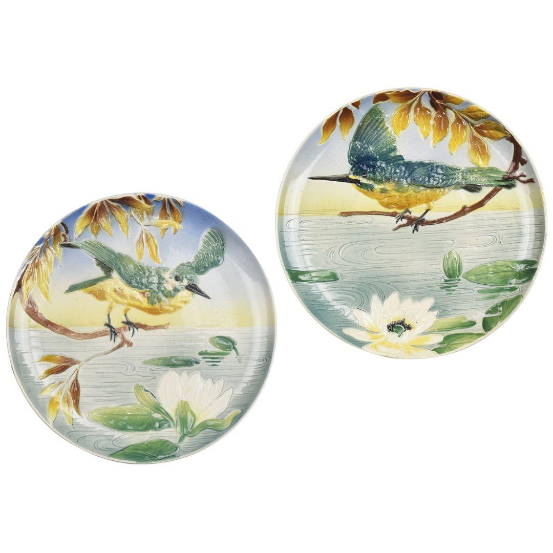 A lovely antique pair of large Art Nouveau decorative majolica wall plates with kingfishers sitting on branches above a lakeside with waterlillies by unknown manufacturer, probably French.