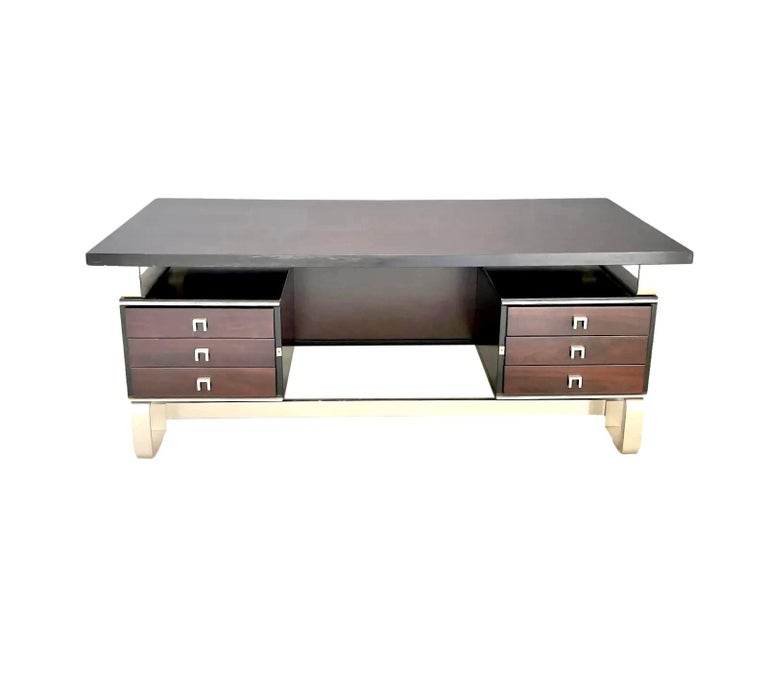 Stunning Italian executive desk in a dark Rosewood. Three pull-out drawers flank each side. Lockable drawers with original locks. Solid aluminum frame with unusual, rounded corners on the base. Matching rounded metal pieces separate the desktop from