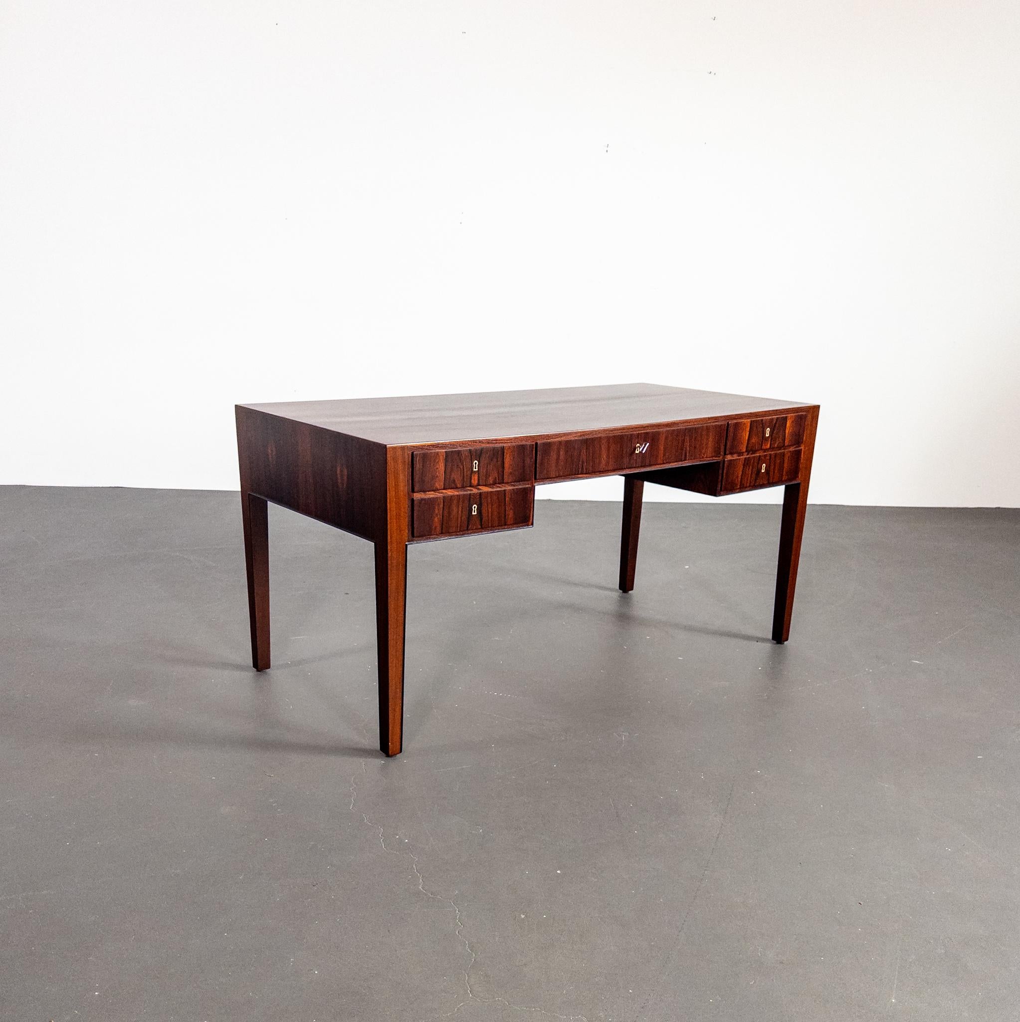Un raro y refinado escritorio ejecutivo diseñado por el renombrado arquitecto danés Ole Wanscher en la década de 1960. Fabricada en exquisito palisandro de Santos (Jacaranda), esta pieza muestra la elegante sobriedad y la artesanía superior que