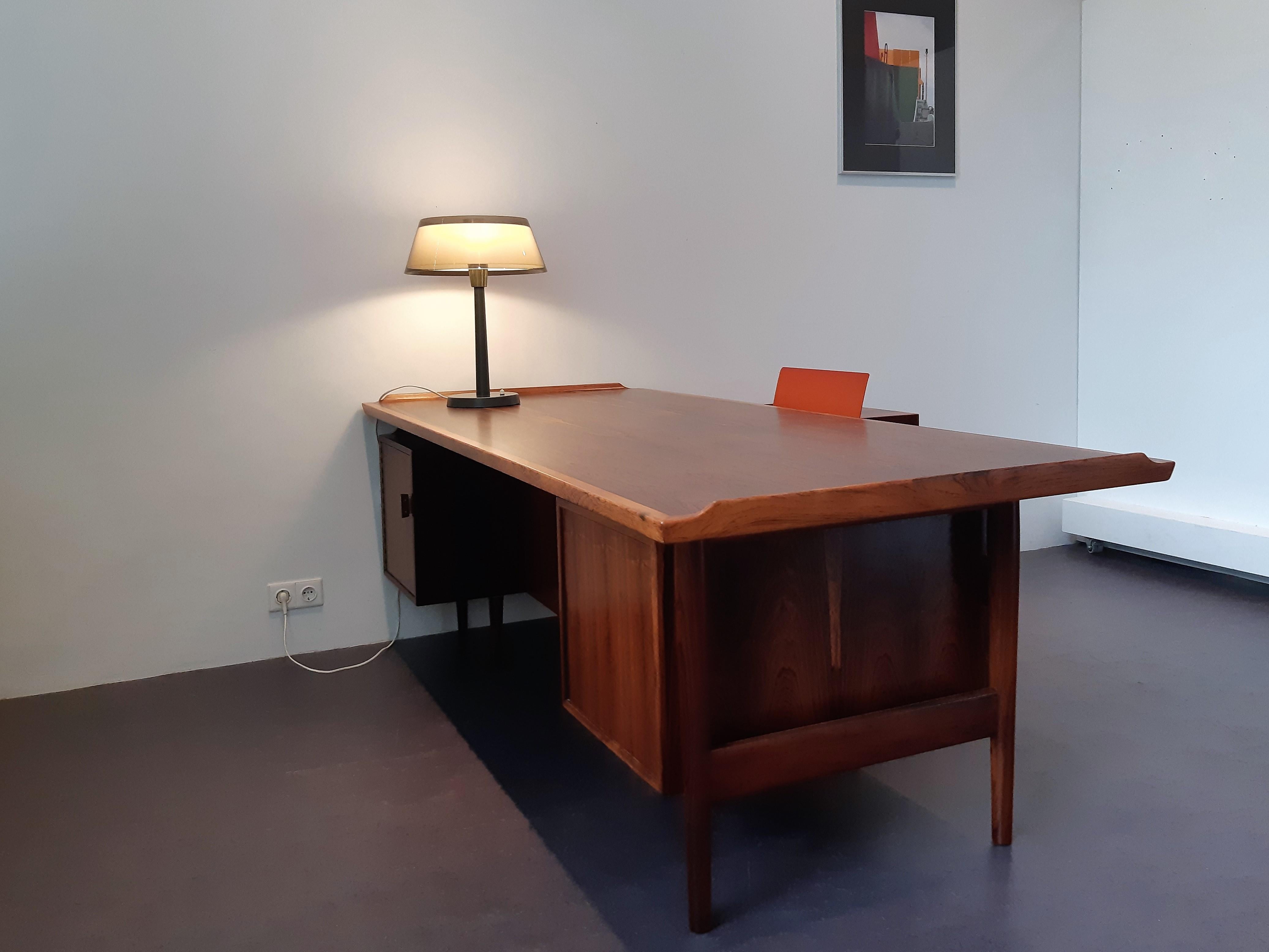 This superb writing desk with integrated sideboard, model 209, was designed by Arne Vodder for Sibast Møbelfabrik in Denmark. It is made out of premium rosewood and has a beautiful top with refined raised edges. The desk has two drawers and a niche
