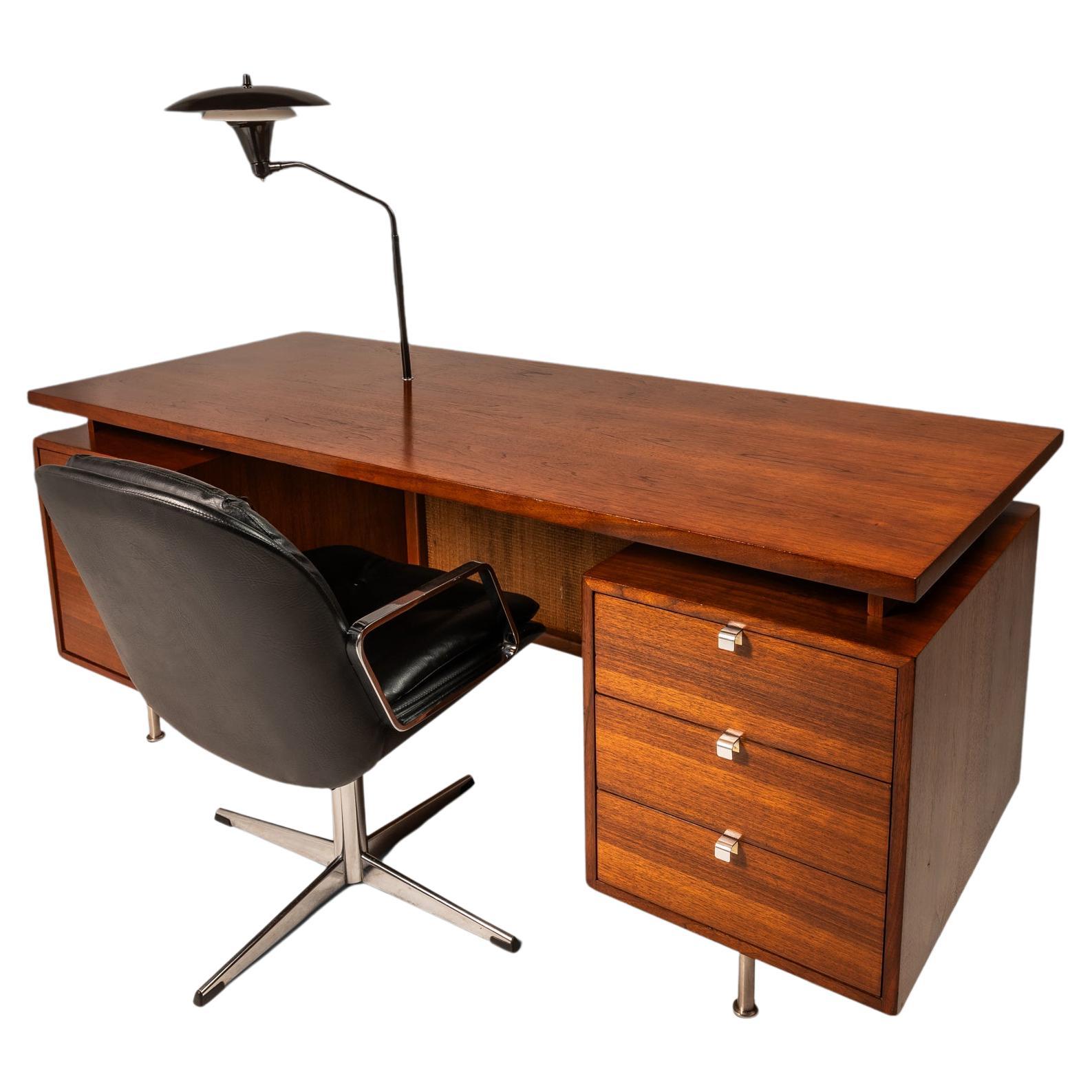 Introducing an icon of American Mid-Century Modern design: an expansive executive desk designed by the iconic George Nelson for the legendary Herman Miller Company. Built from a mix of solid and veneered walnut and featuring a cane front as well as