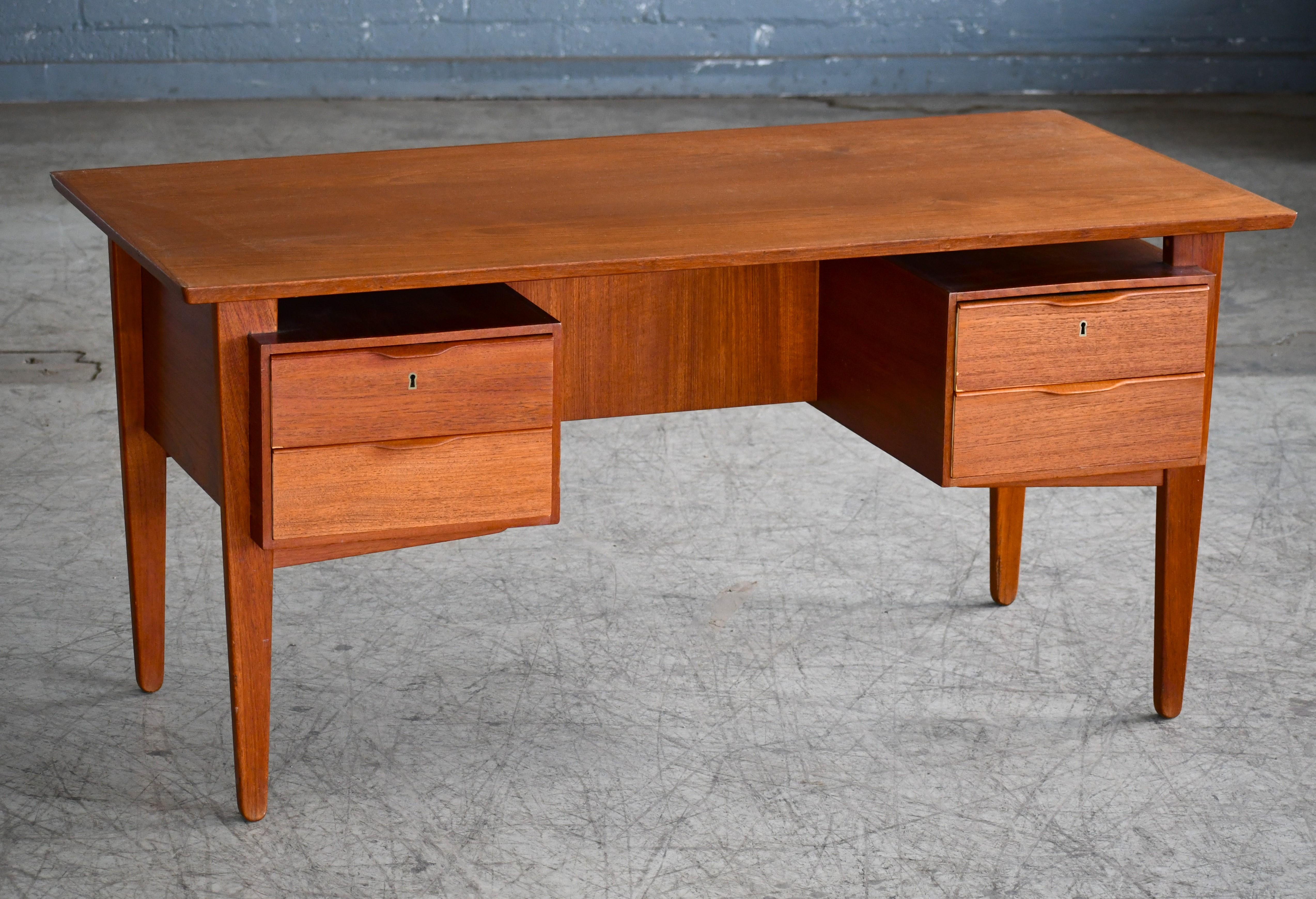 Very beautiful designed executive desks In the style of Gunni Omann's Model 75 and Kai Kristiansen's Model 60. Classic Made of solid and veneered teak. The desk features a desk top that floats over the base. The base has three drawers on either side