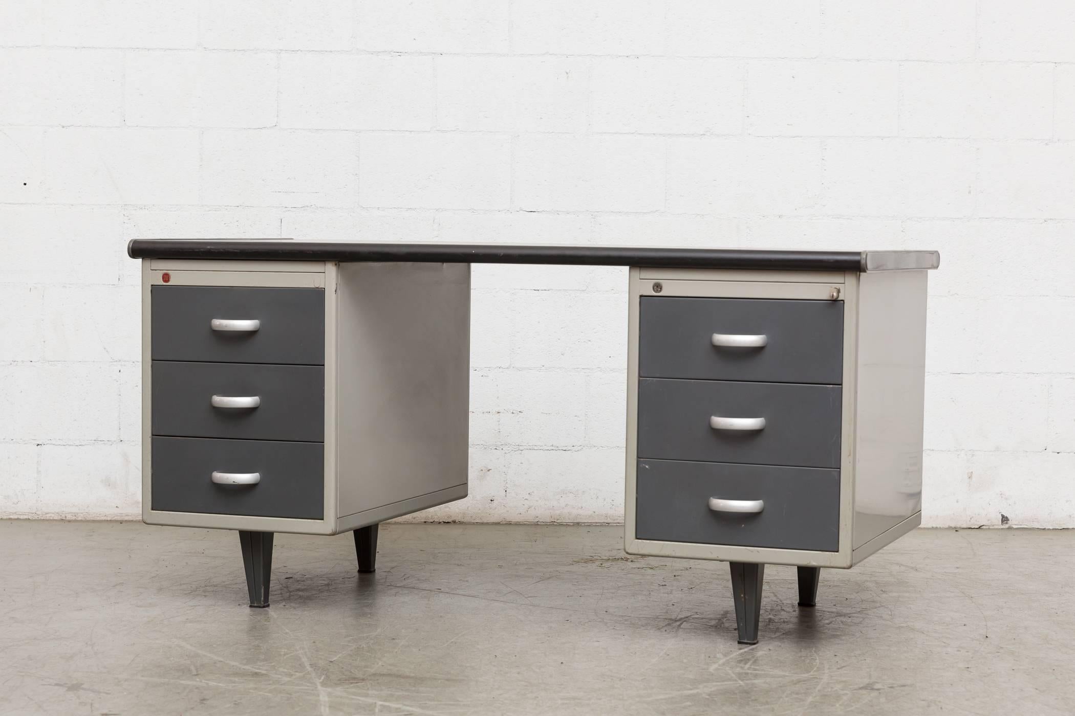 Very cool midcentury Gispen Industrial metal desk with linoleum top, light grey enameled metal frame and dark blue-grey-ish double stacking drawers. Original owners stickers still inside the drawer. Manufacturers logo on top left side (as pictured).