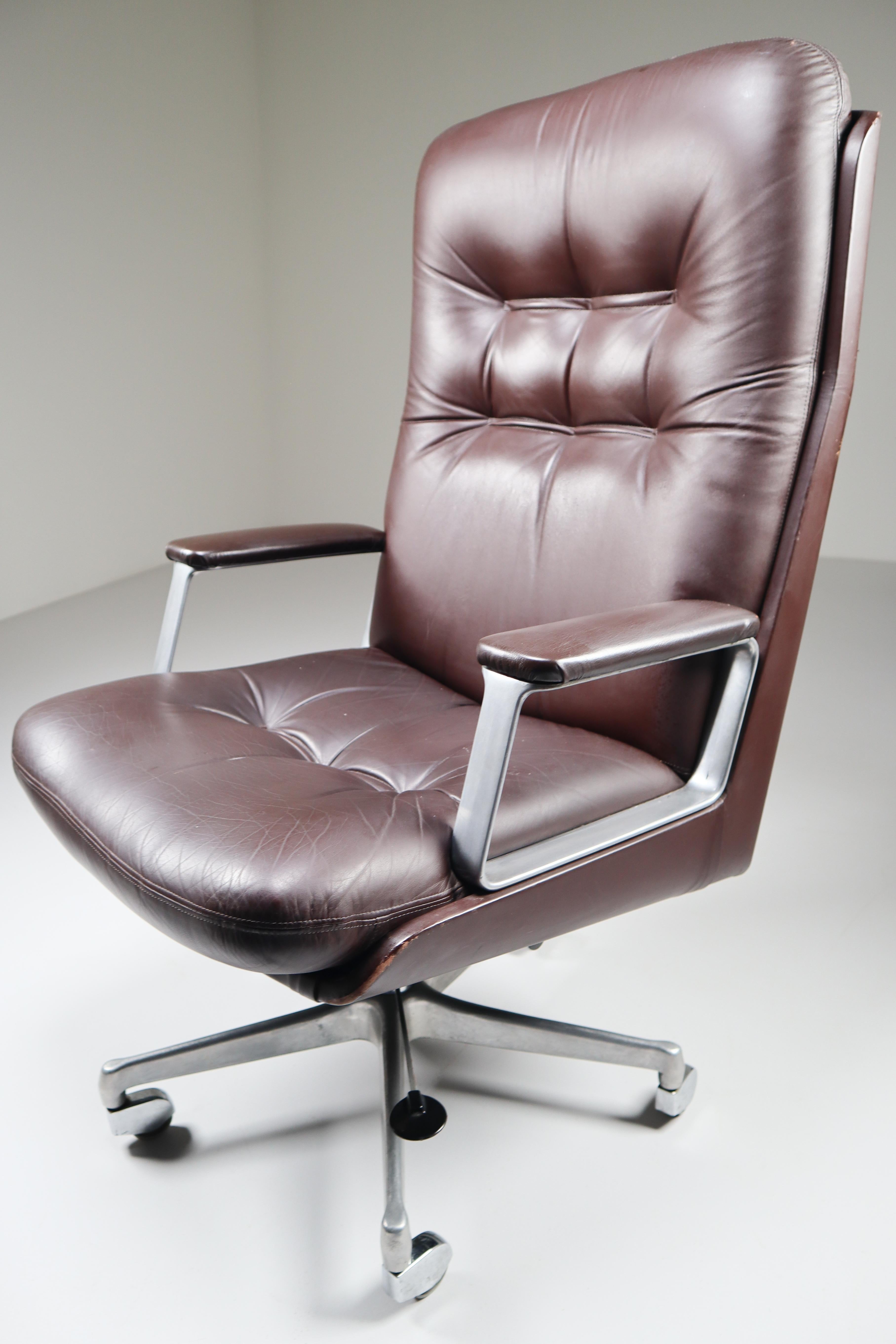 Executive office high back chair by Osvaldo Borsani for the Italian manufacturer Tecno features a maroon brown leather body with a generously proportioned button-tufted leather seat and back and floating on a five-pronged rolling adjustable cast