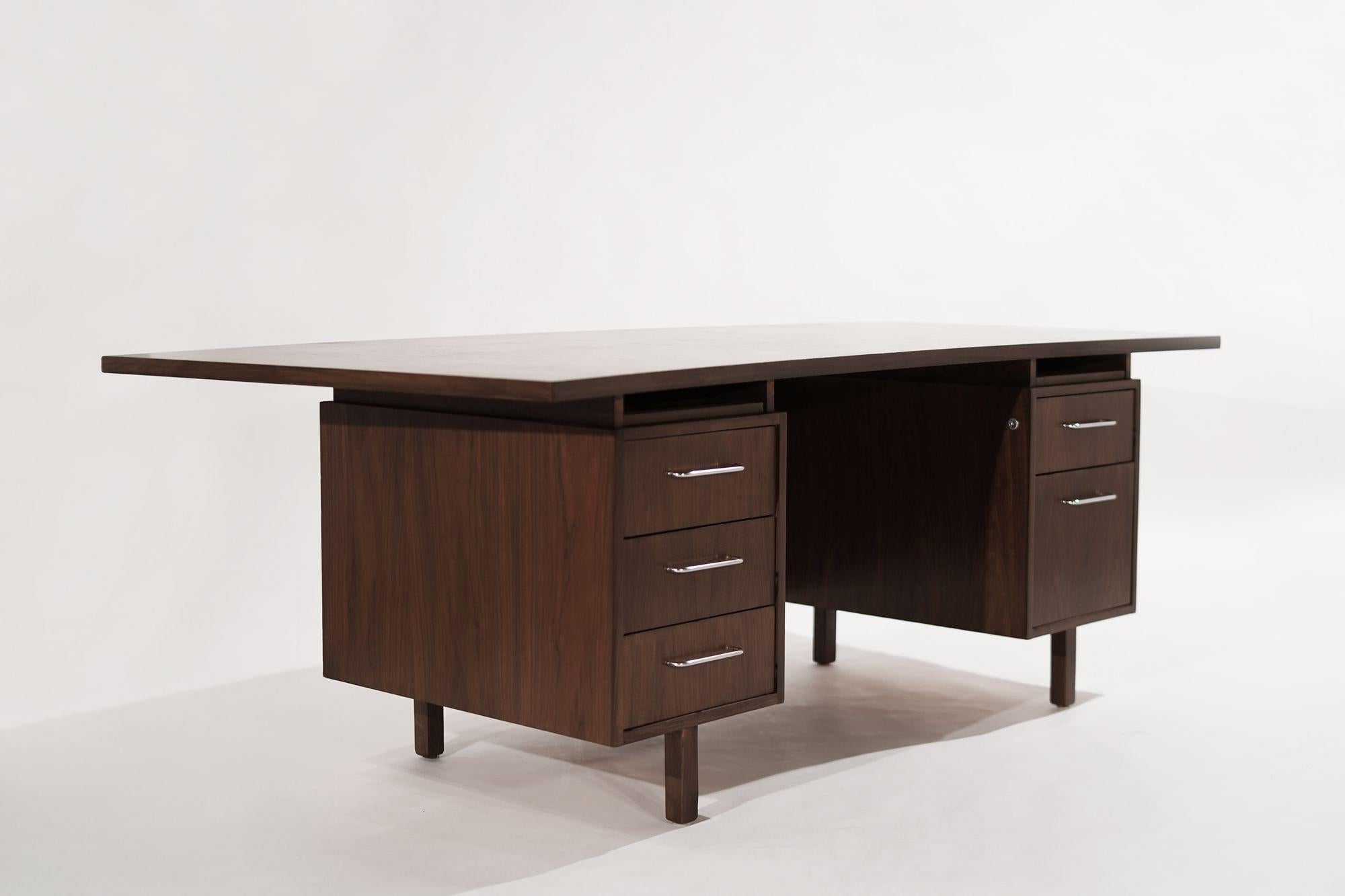 A large-scale desk executed in walnut, designed by Harvey Probber, circa 1950-1959. Completely restored to its original finish and functionality, featuring a con-cave top and nickel hardware. Coated with our special scratch and water-resistant