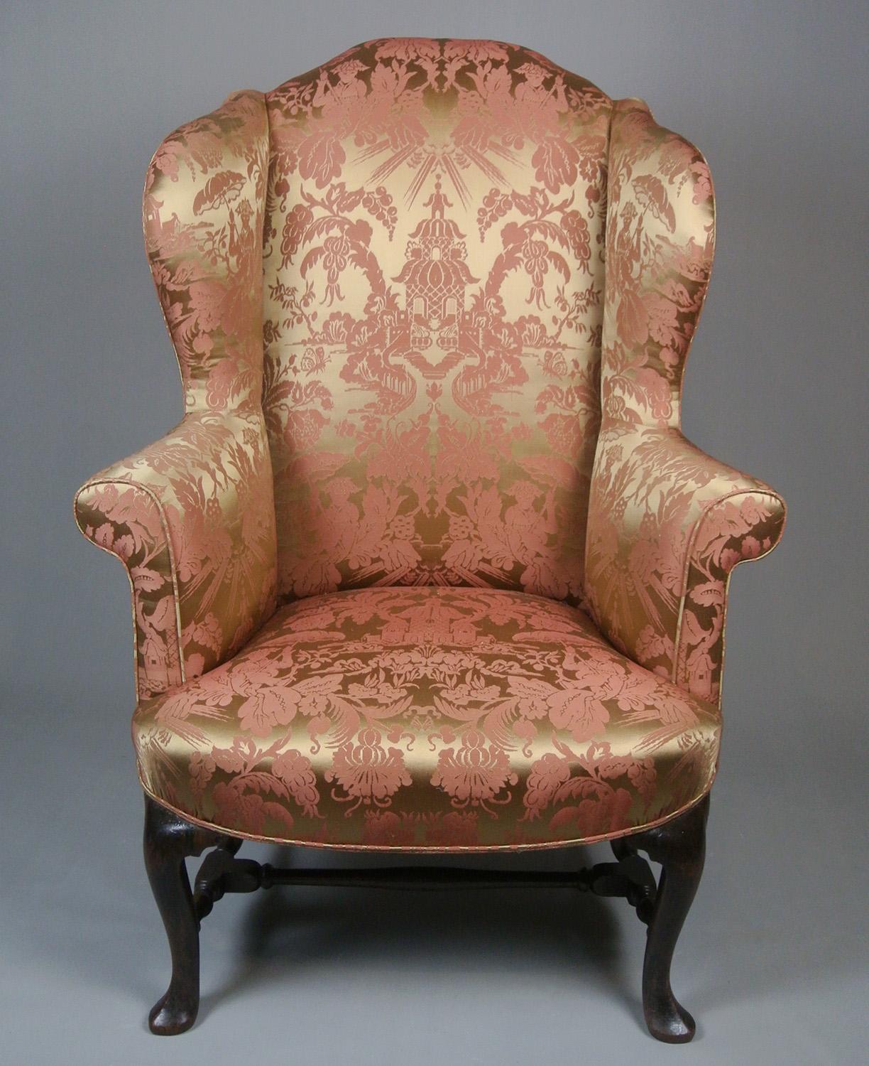A very fine early 19th Century mahogany wingback armchair dating from c. 1715 with tall, elegant, slightly cabriole legs to the front terminating in puddle-pad feet and raked legs to rear and joined by finely turned original stretchers.

 The tall