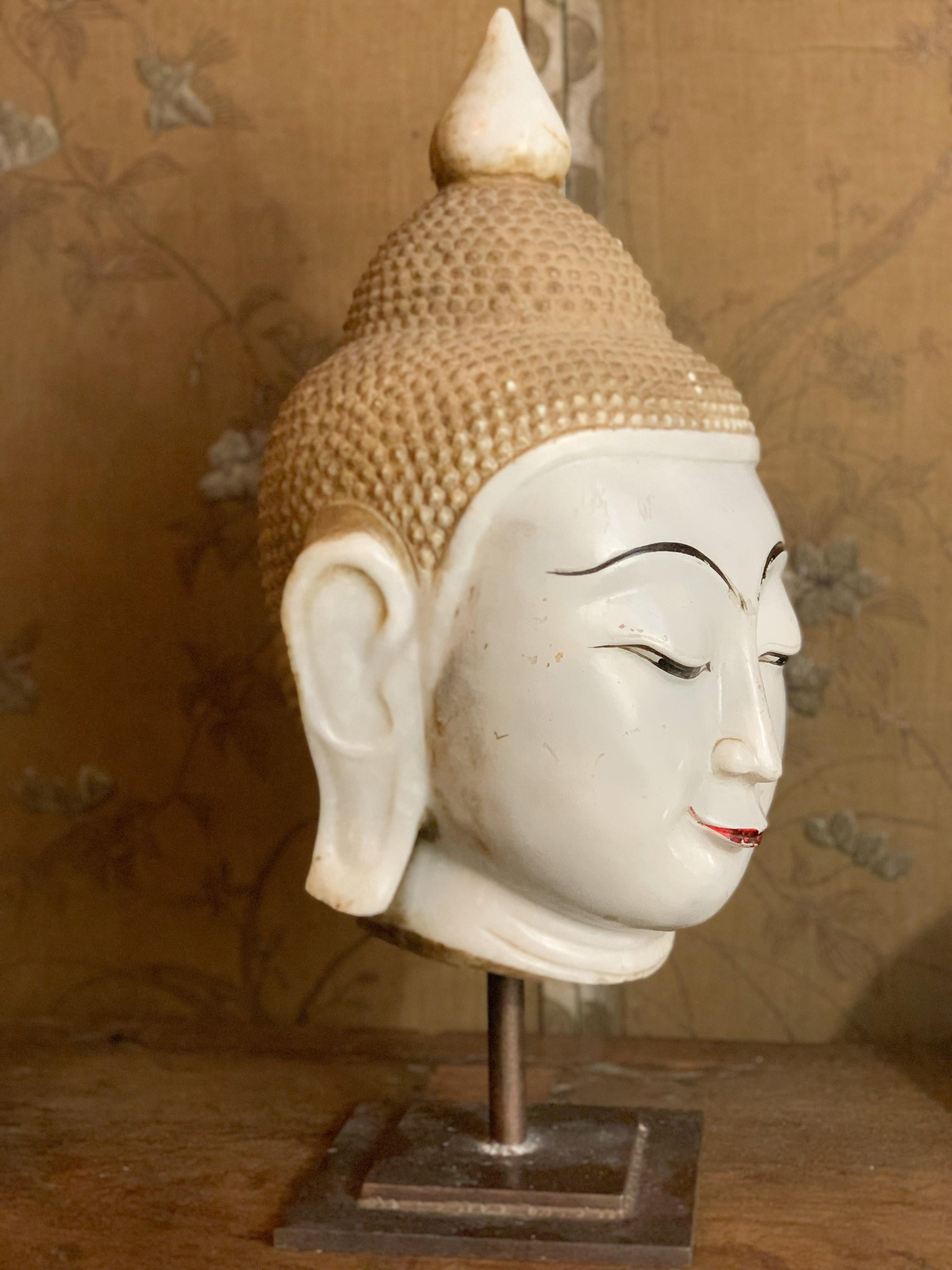 Important Burmese Buddha head in lacquered and gilded marble. Buddha represented half-closed eyes symbolizing the look inside oneself, symbol of wisdom and serenity and sketching a smile symbol of beatitude. The golden headdress is composed of fine