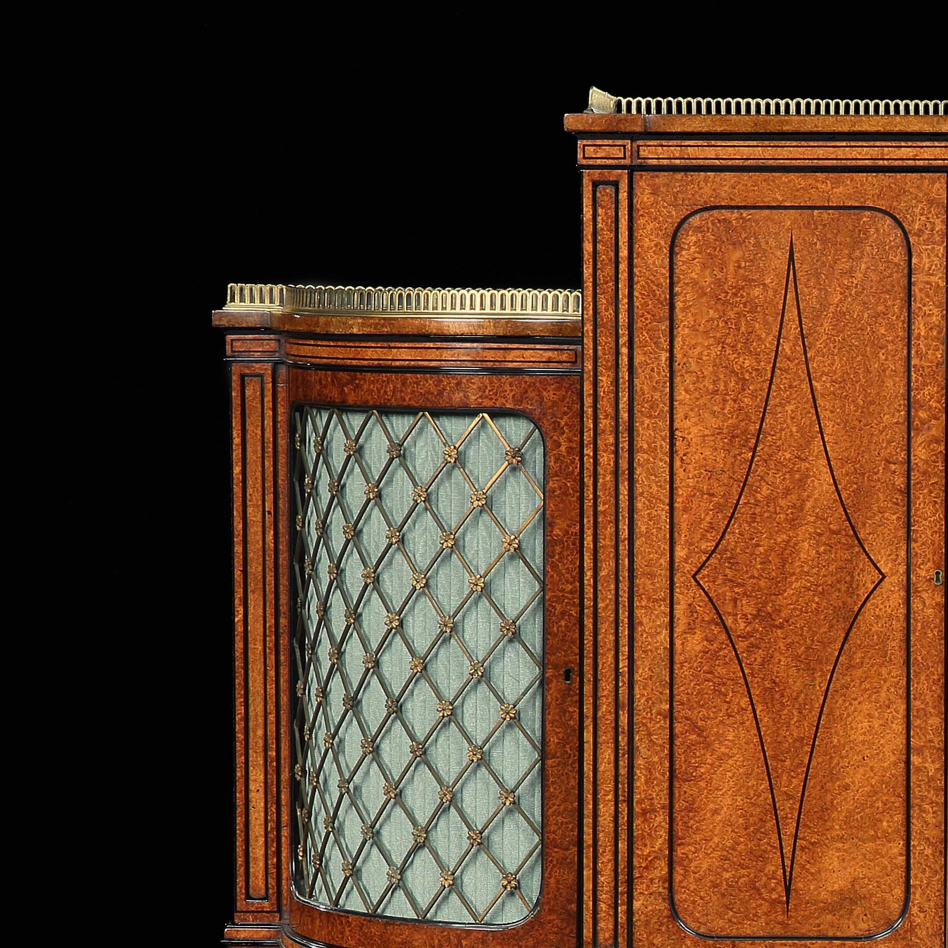 An exhibition quality 19th century Ormolu-mounted Amboyna and ebony shaped side cabinet on tapering legs, circa 1860.

This superb cabinet being finely decorated with ebony beading and stringing having a raised upper section with a pierced brass