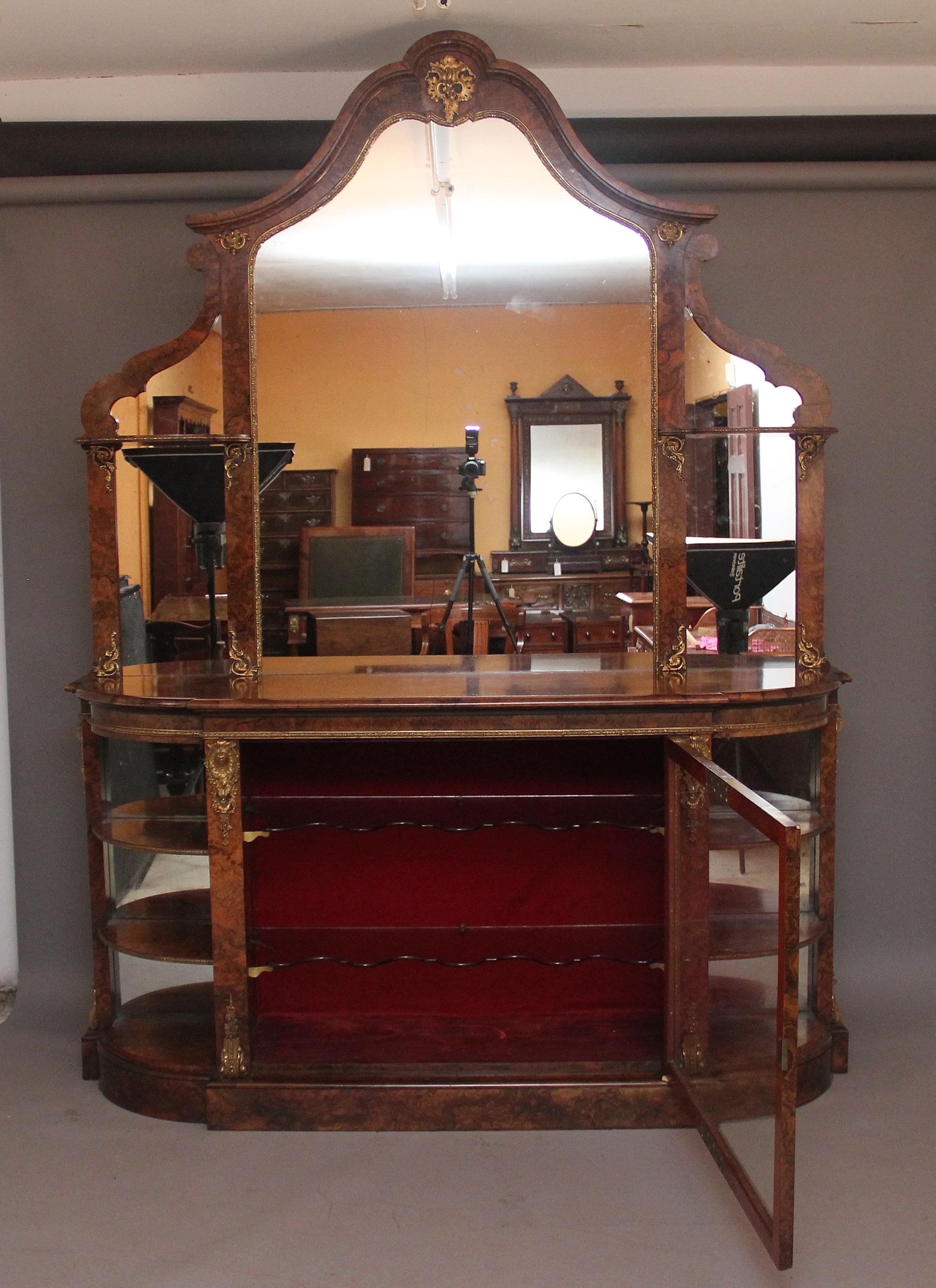 An exhibition quality 19th Century burr walnut mirror back credenza, the shaped mirror back top comprising of a large central mirror and two smaller mirrors either side, decorative arched top and shaped frame incorporating a large ormolu mount at