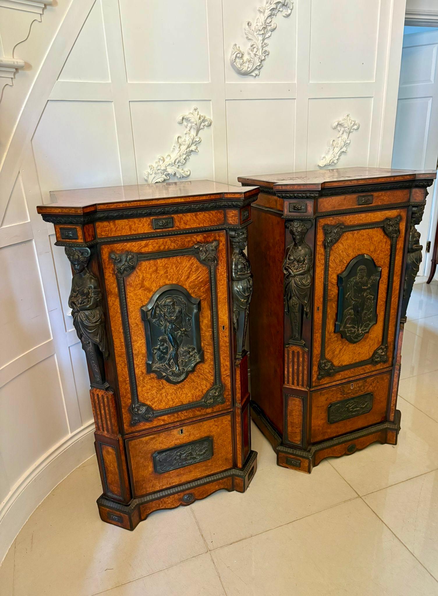Coppia di piedistalli antichi vittoriani in amboyna ed ebano intagliato di qualità espositiva con piano in amboyna con bordo incrociato sopra un cassetto a fregio e un'anta singola che si apre per rivelare un ripiano interno sopra un piccolo
