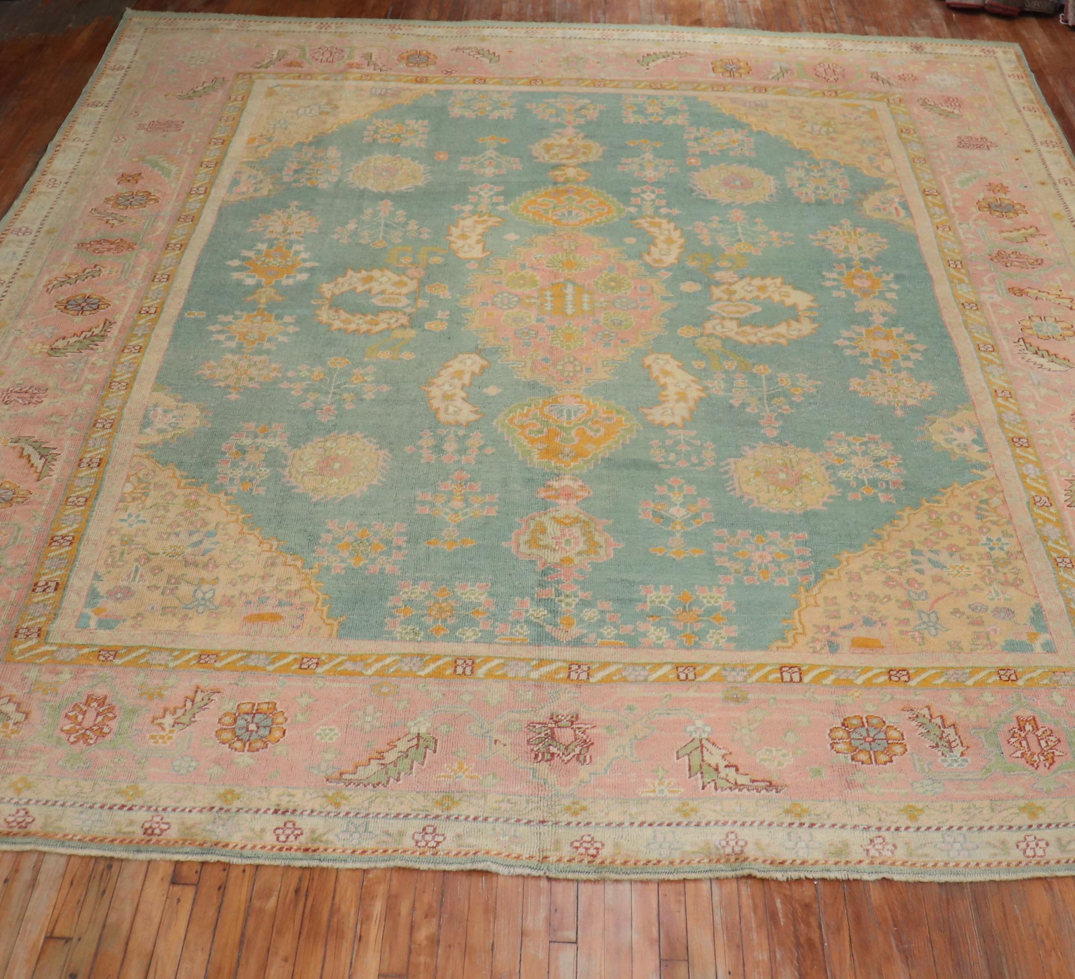 A colorful antique early 20th century Turkish Oushak rug. The field is teal; the border is pink. The rug has a lot of character and exhilarating in person

Measures: 13'4” x 15'8”

Antique Turkish Oushak rugs have been woven in Western Turkey