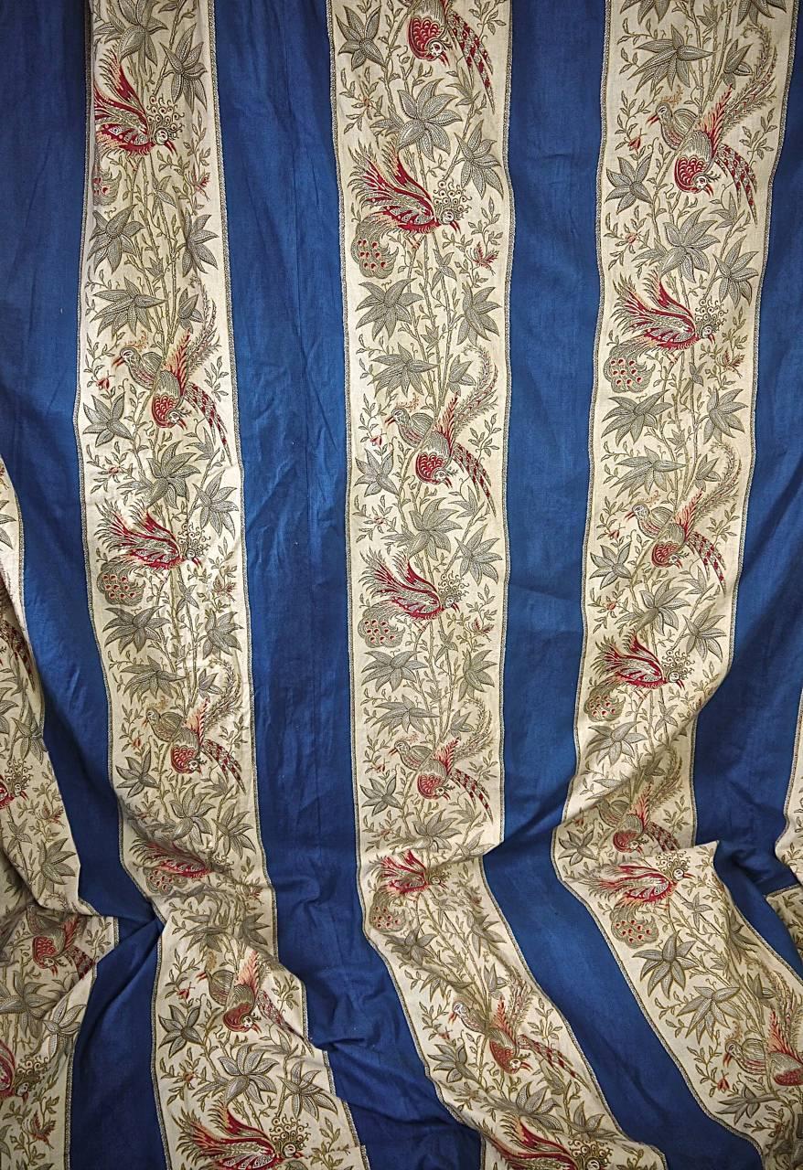 French antique cotton very large curtain with a design of exotic birds and leaves alternating with a blue stripe. Its original use probably hanging from a curl de lit around a bed. Beautifully gathered at the top and edged with a wool trim.
 