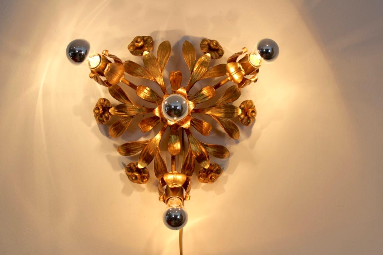 Exotic Hollywood Regency style gilt floral flush wall lamp. Designed in Germany by Hans Kögl in the 1970s. This classy and rare lamp has three lights mounted in beautiful gilded floral metal leaves. Decorated with gold leaves. It is in an excellent
