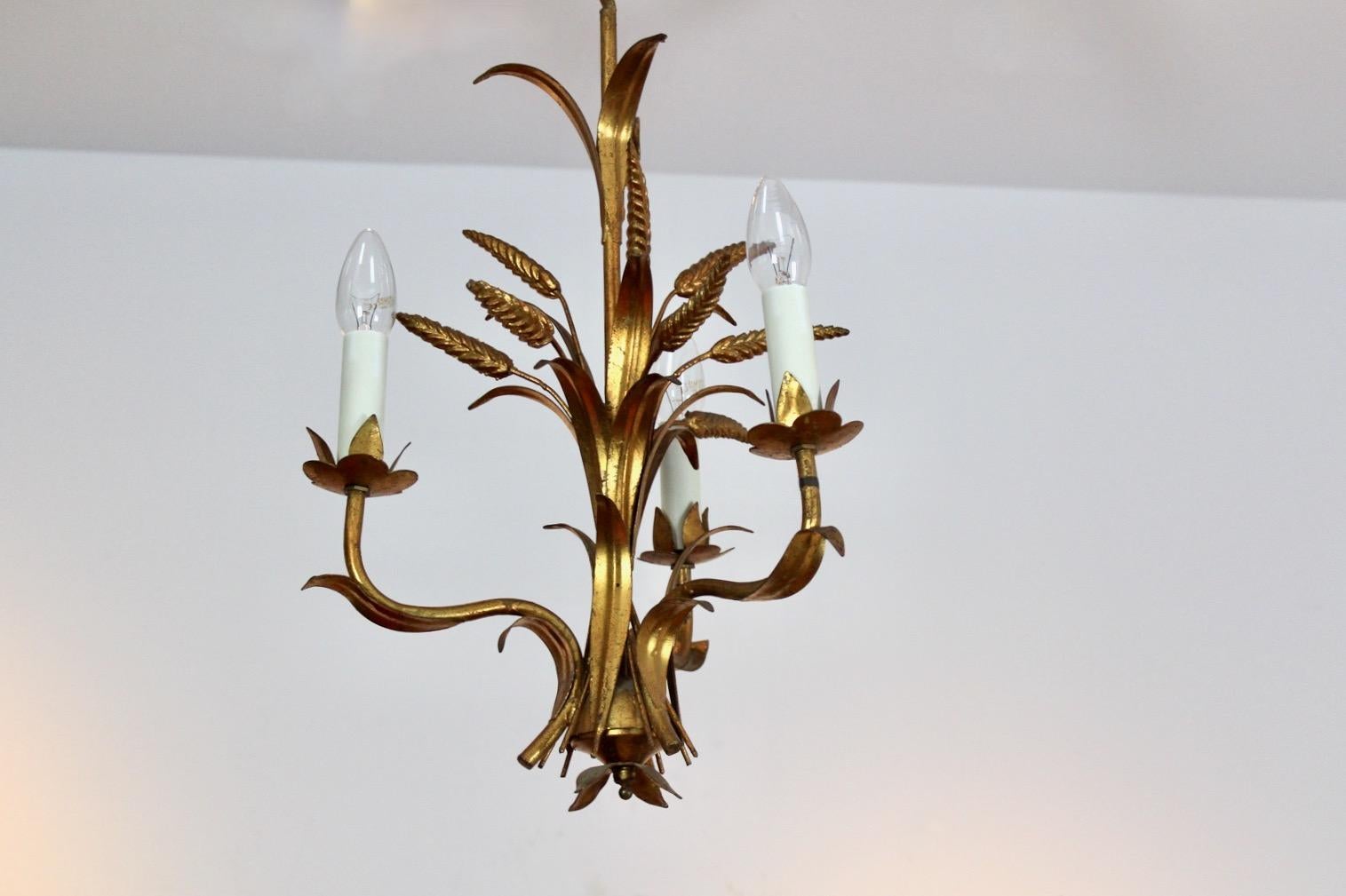 Exotic Hollywood Regency style gilt wheat sheaf chandelier. Designed in Germany by Hans Kögl in the1970s. This classy and rare lamp has three lights mounted in holders with faux candle covers and beautiful gilded floral metal leaves. The lamp is