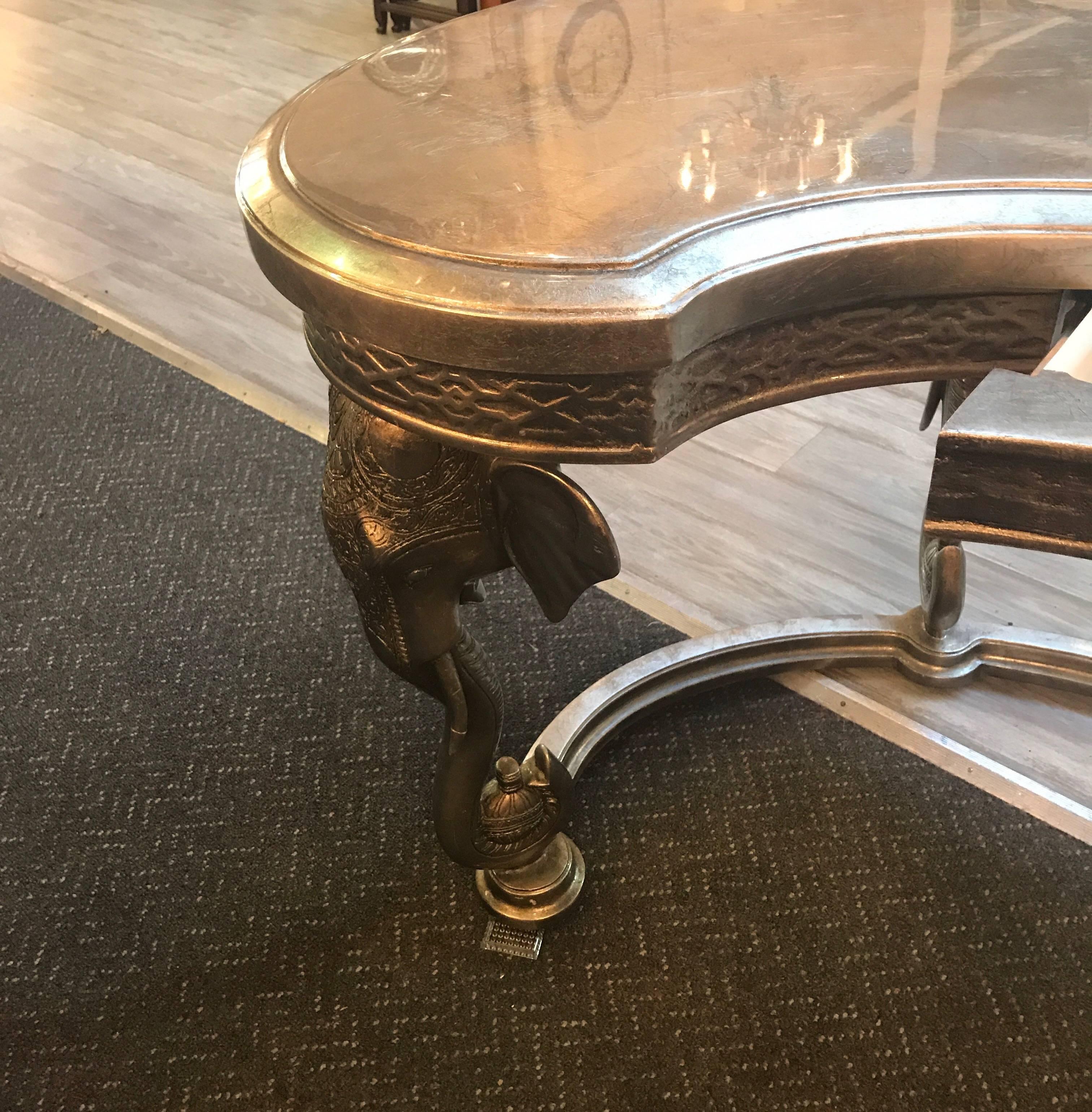 High style silver leaf kidney shaped witting desk with elephant motif legs. The glossy top with one central drawer supported by four elephant head legs. Made by Maitland Smith.