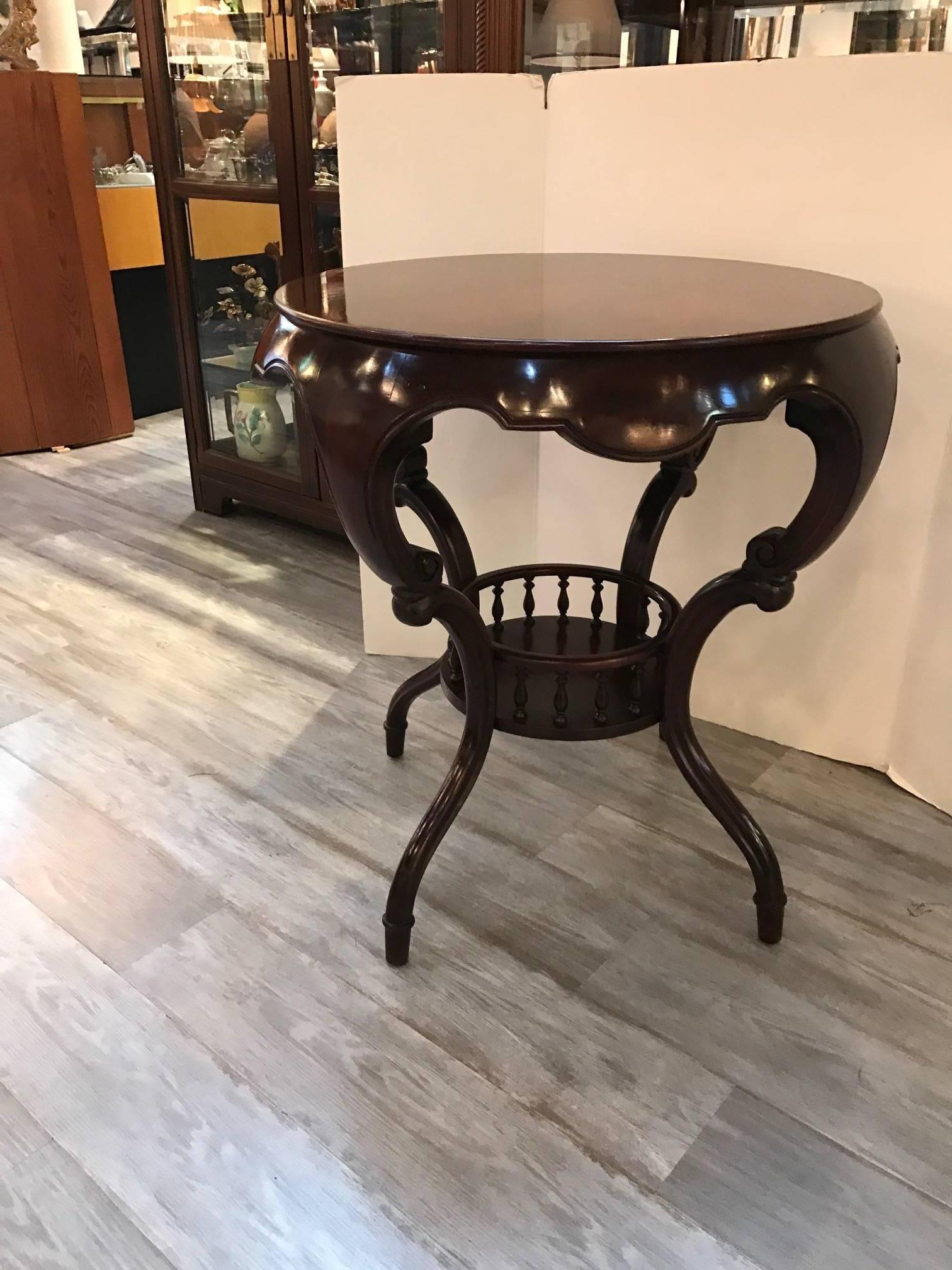 Shapely round side table with bookmatched mahogany grained top. Carved knees and tapered feet support this graceful table. Beautiful deep scalloped apron all around this decorator table has a slight Asian feel which will fit almost any style room.