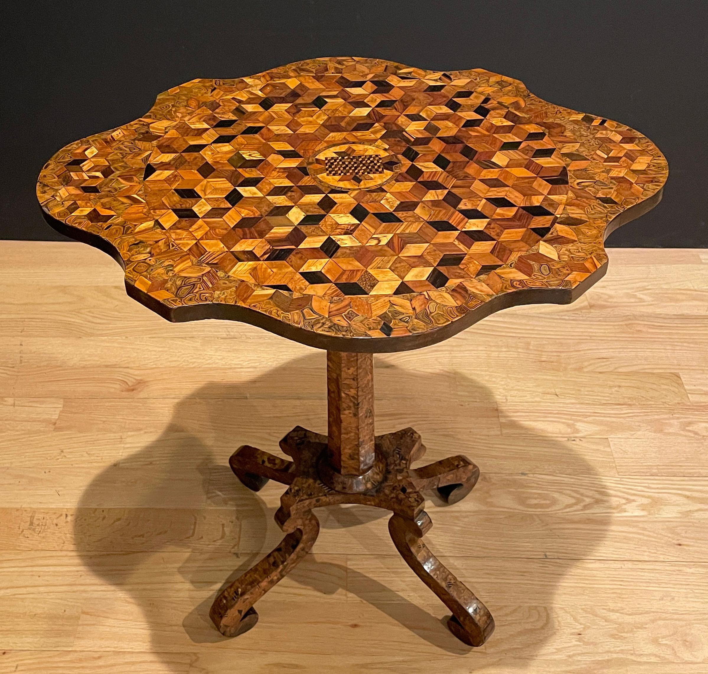 Exotic and unusual specimen wood parquetry scalloped oval pedestal table. Able to be used as a petite center table, candle stand /wine stand or side table. Four legs and tapered column supporting a beautiful and visually 3-dimensional specimen wood