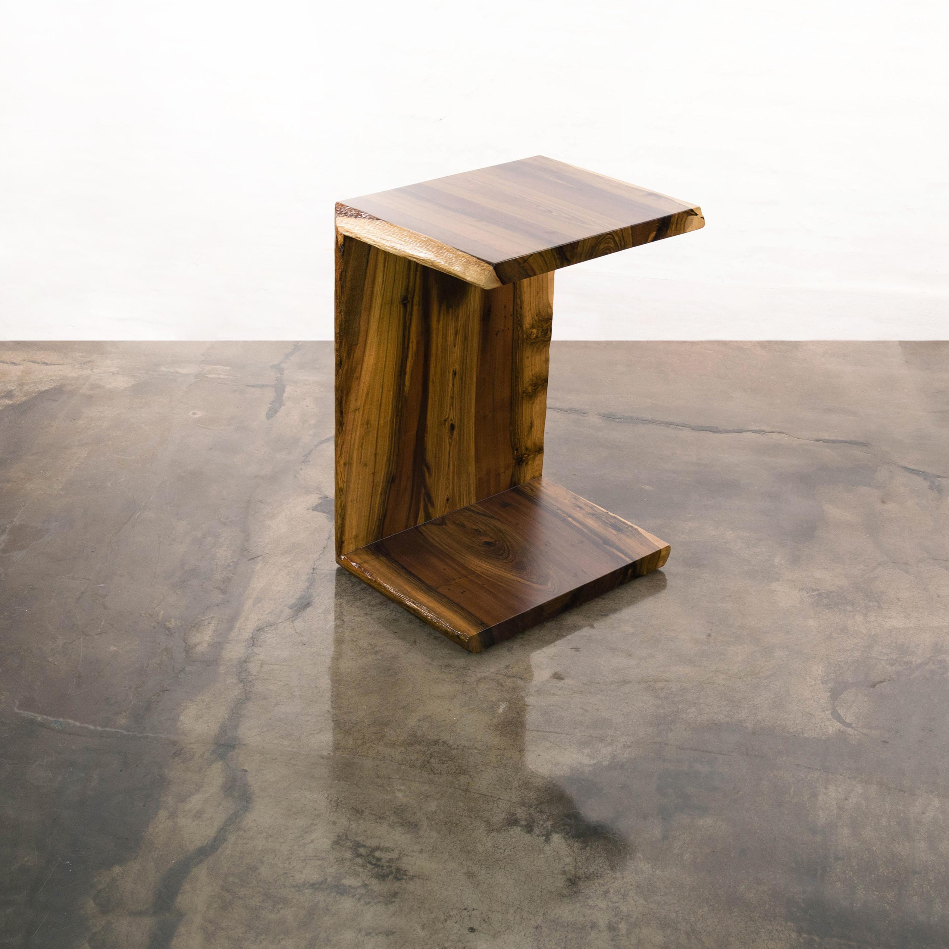 Designed to slide under a sofa or sitting area as necessary, the Carlo Table is a cantilevered occasional table fashioned from live edge wood. Shown here in Argentine Rosewood and also available in walnut. Inquire for details of current wood stock