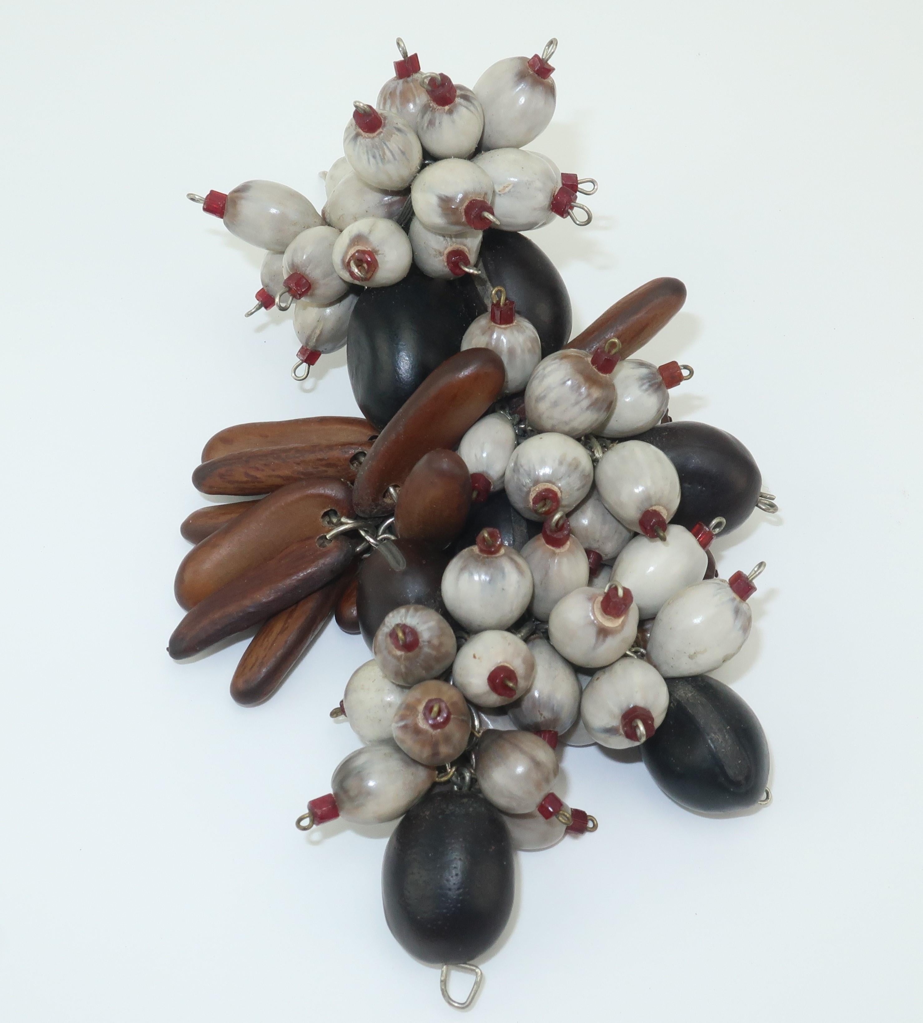 At one time dress & fur clips were all the rage providing an ornamental accent to everything from clothing to hats.  This unusual clip has an organic composition with wooden style beads that are actually seeds and pods wired with micro beads and