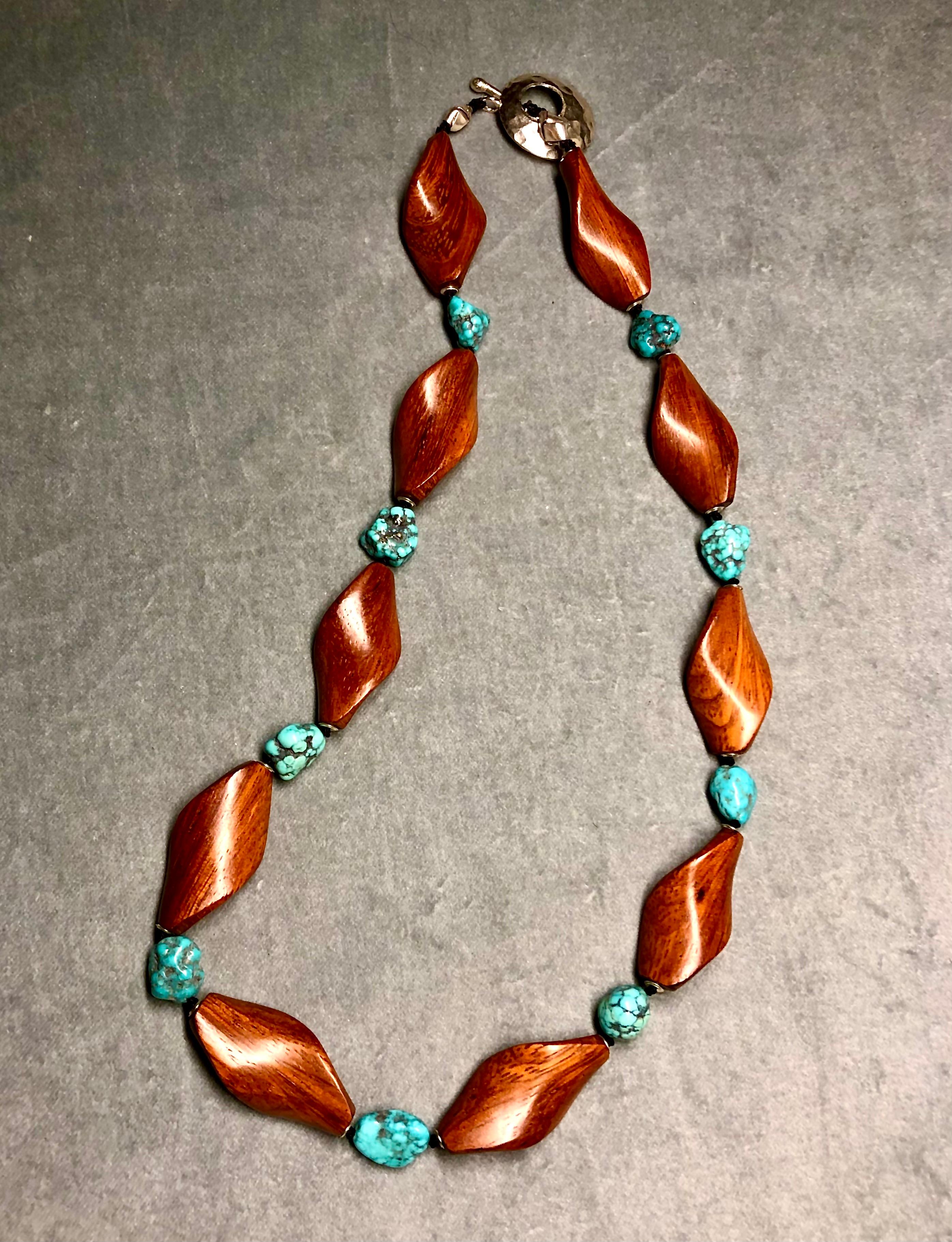Single strand necklace, spiral carved exotic wooden beads flanking spider veined turquoise tumbled nuggets themselves flanked with sterling silver rondelles. Finished with sterling silver toggle clasp. 
