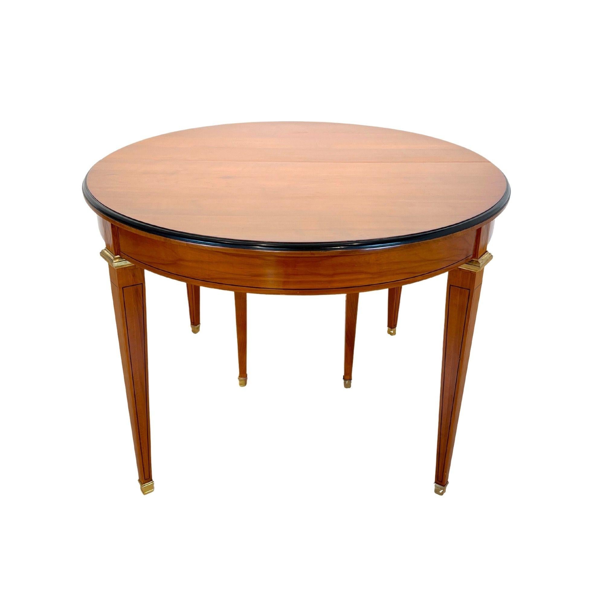Late 19th / early 20th century Biedermeier / Restoration style expandable dining room table.
Solid oval cherry top, expandable with 3 inlay plates. Schellack hand polished.
Conical square tapered legs in cherry wood with ebony band inlays. Original