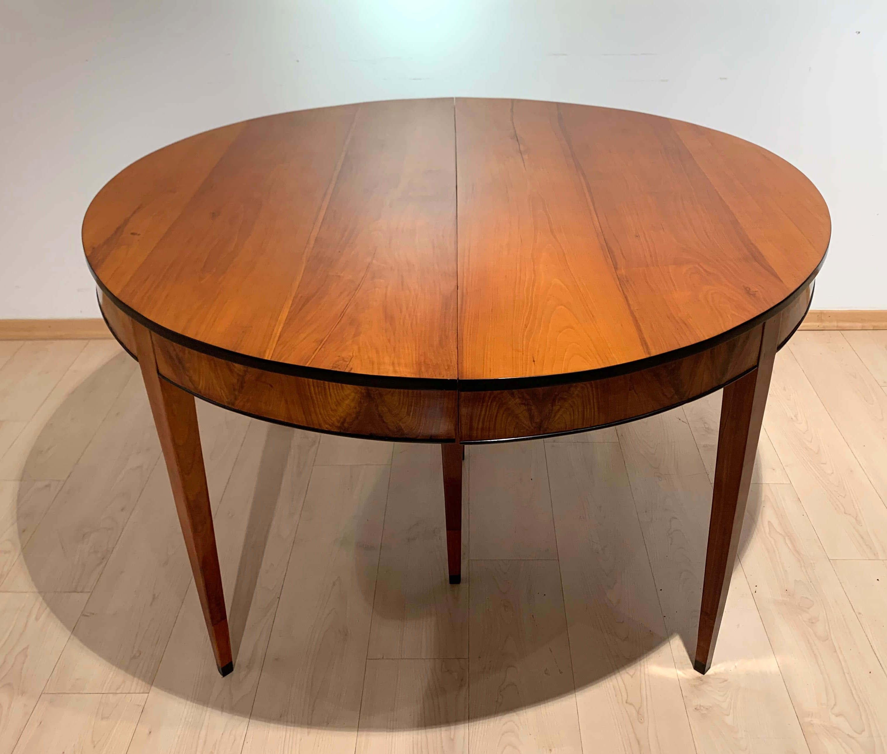 Elegant, round, expandable / expanding neoclassical Biedermeier dining room table in cherry solid wood and veneer, from Southwest Germany about 1820.

Exquisite cherry solid wood on the plate and legs as well as book-matched cherry veneer on the