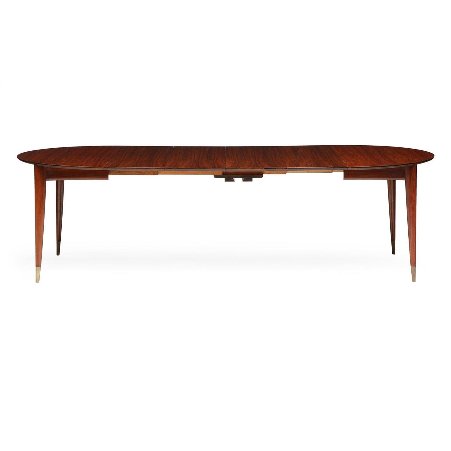 Une belle et rare table de salle à manger extensible en noyer au grain vif, avec un épais plateau biseauté et des pieds triangulaires sculptés avec des sabots en laiton. Le tableau comporte quatre feuilles.