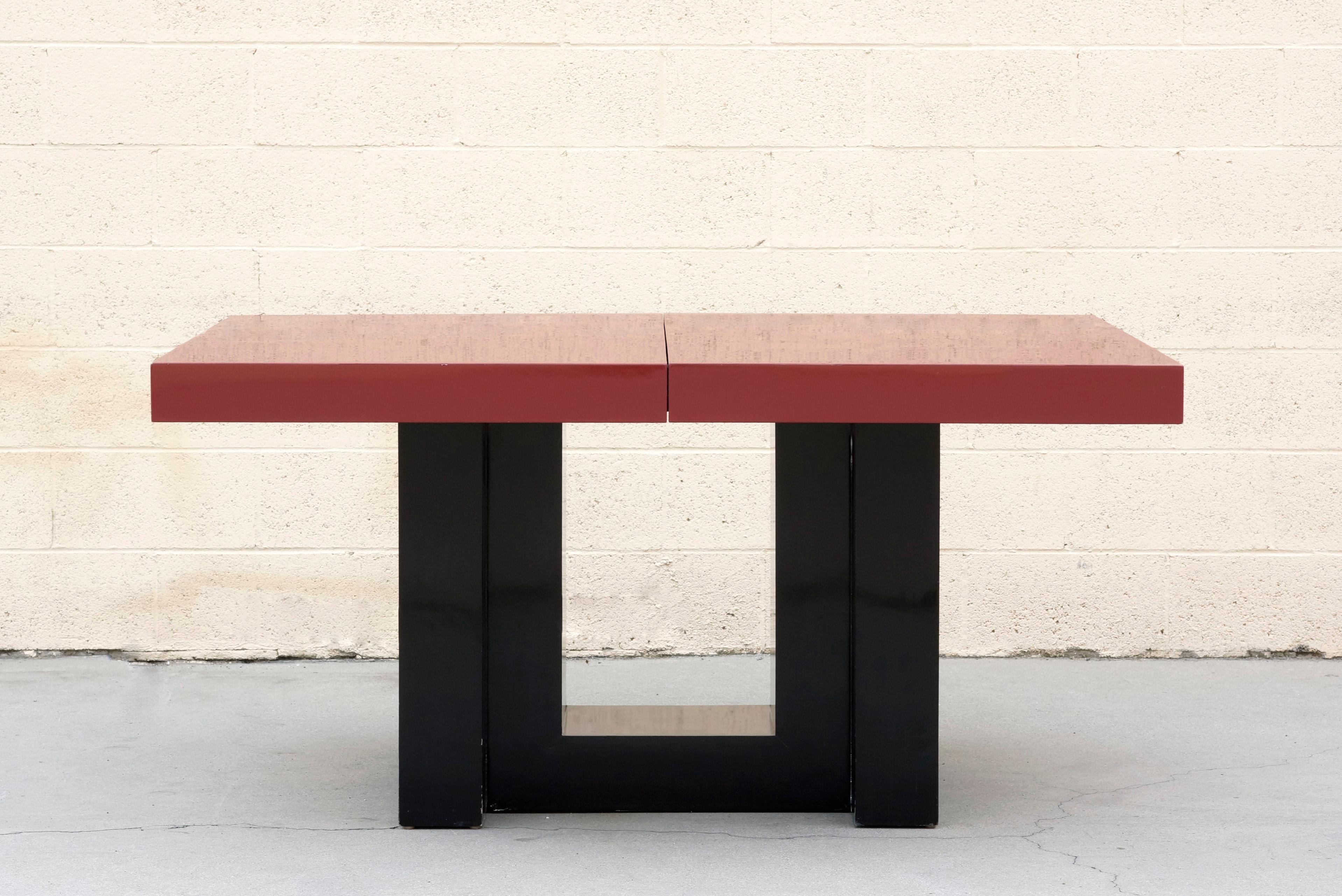 Beautiful Art Deco dining table designed by Paul Laszlo, 1940s. Oversized expanding top and sculptural base in a two-tone black and maroon lacquer finish. Includes two leaves at 14