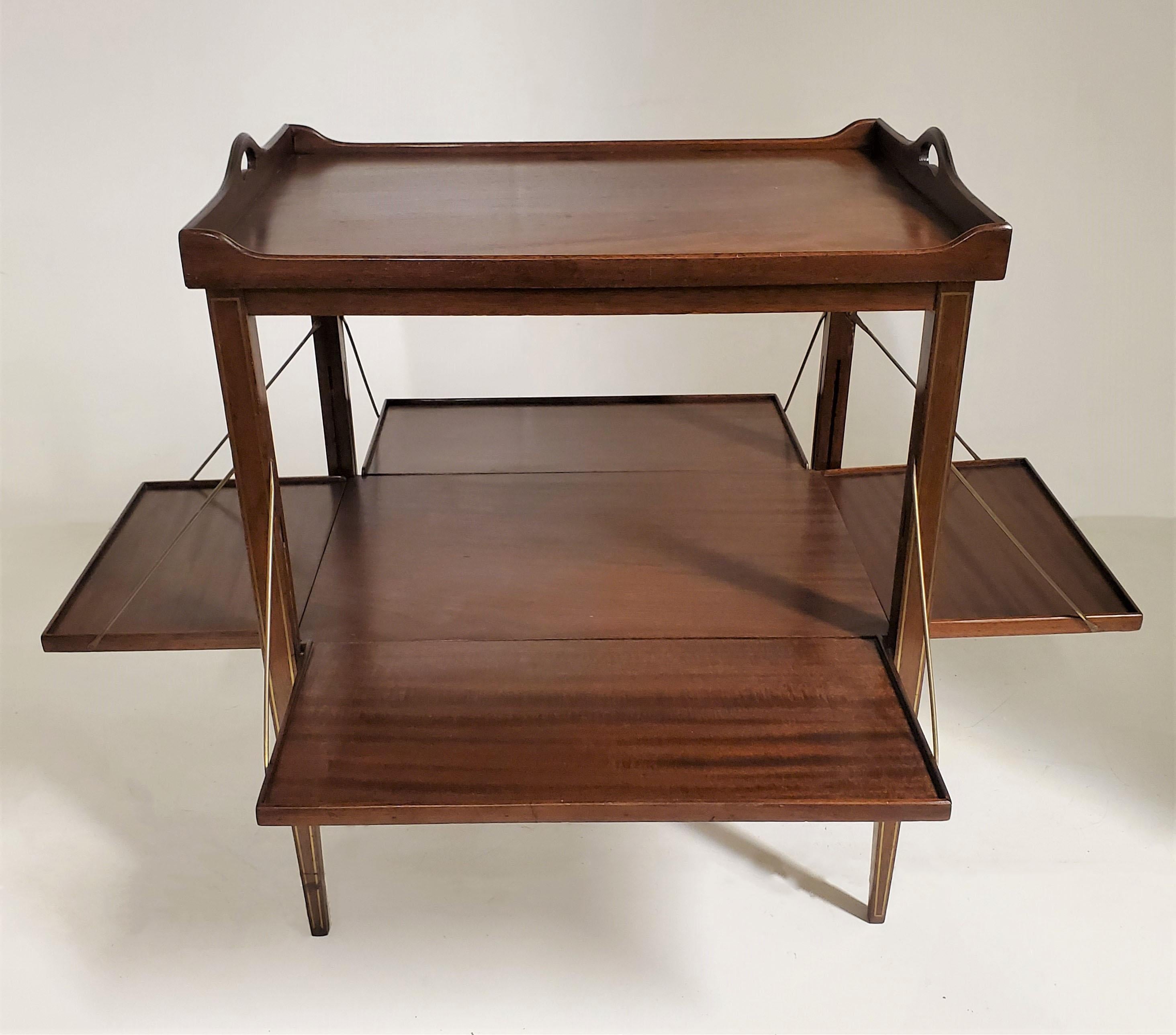 An unusual ribbon striped mahogany side table with brass inlay set into the attached tray frame and along the tapered elegant legs. This table features brass rod supported sides that modify to drop down and expand on all four flanks providing
