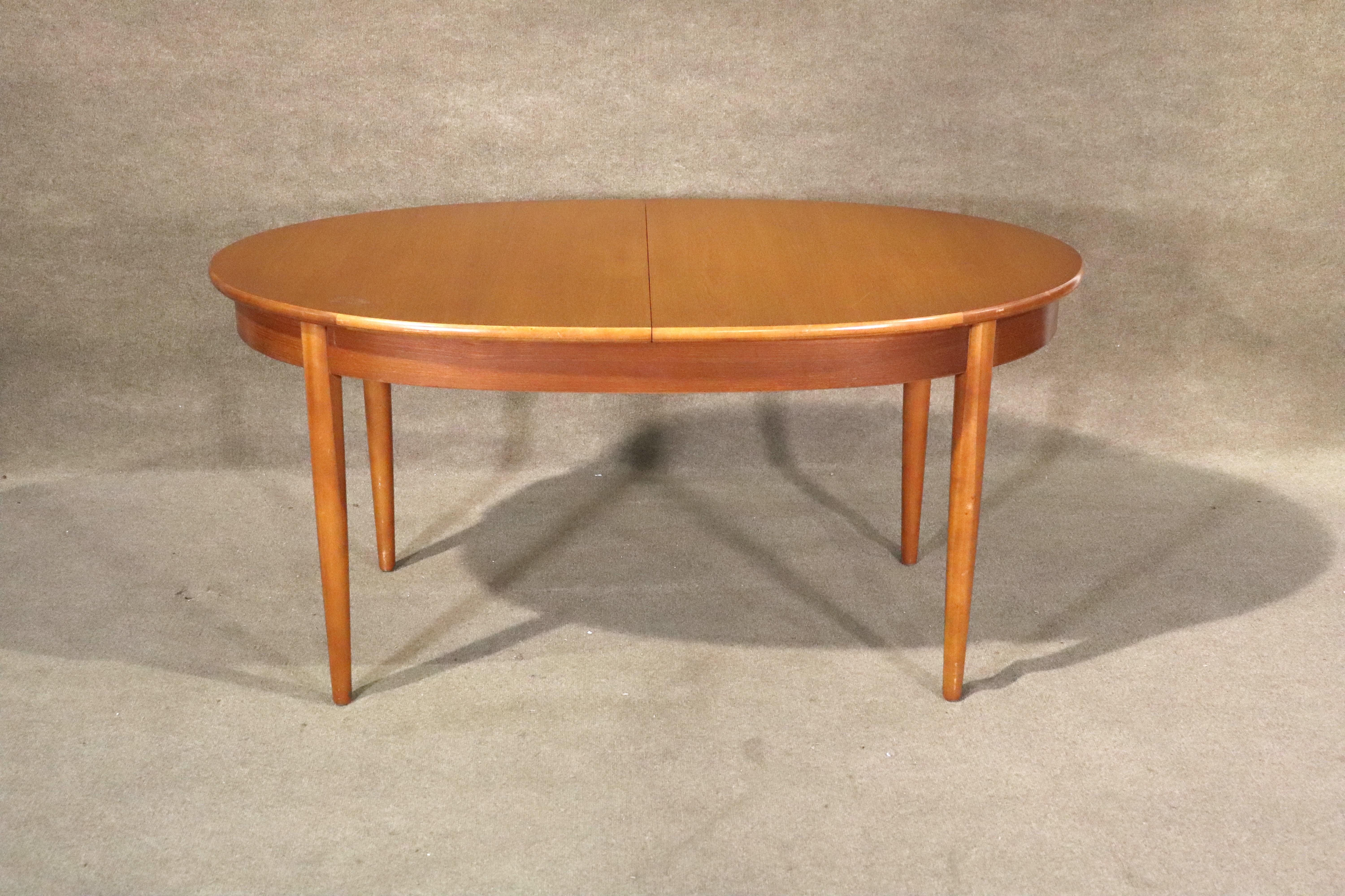 Table de salle à manger ovale avec une feuille papillon à rangement automatique qui se replie facilement dans la table pour un rangement aisé et sûr. Design/One Modern avec grain de bois de teck sur l'ensemble de la pièce. Un design idéal pour votre