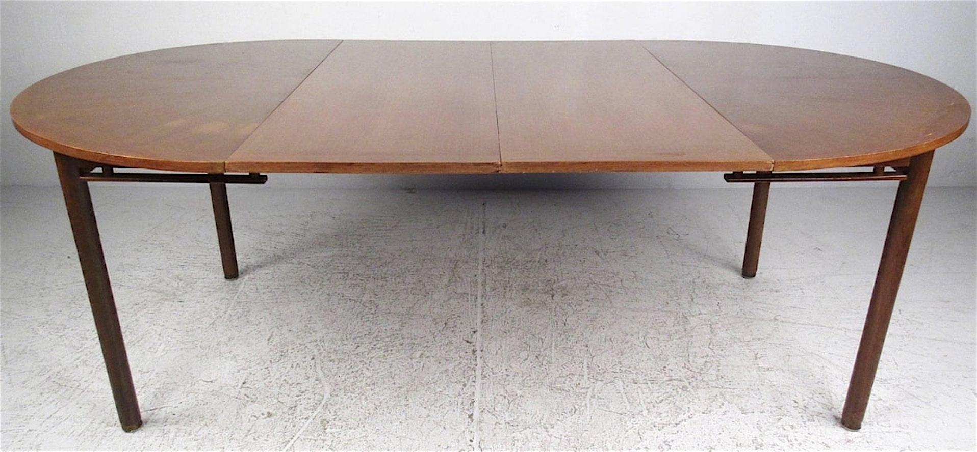This round mid-century modern dining table features radiating marquetry veneer pattern top and two leaves that extend the length to 7 feet.
Each leaf is 18