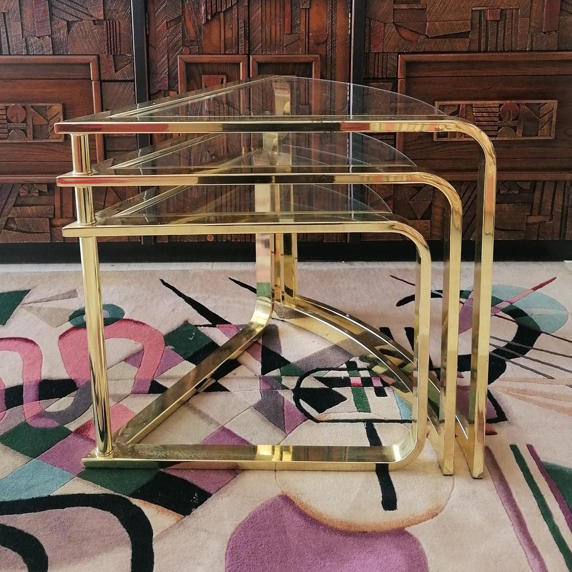 Rare vintage expanding three tier coffee table by Design Institute of America (DIA), 1980s. The 3 wedge-shaped tables are on a central pivot, enabling them to be nested together, or spread out in a circular shape.
Frames are shiny gold metal, with