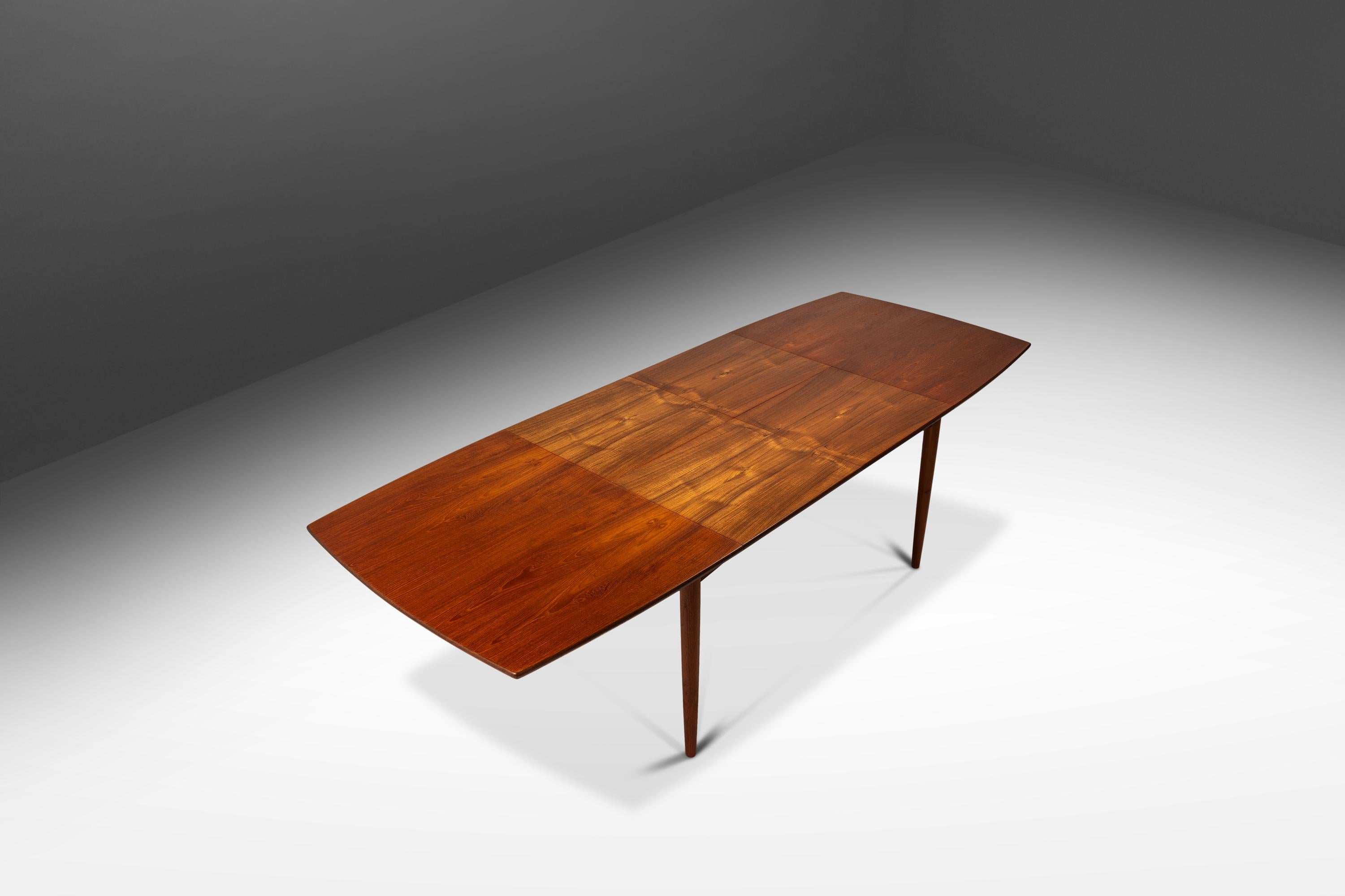 Equal parts beauty and functionality this extraordinary extension dining table is in 100% original, vintage condition and aged to perfection! Constructed from a mix solid and matchbook-veneered Burmese teak with exceptional old-growth woodgrains