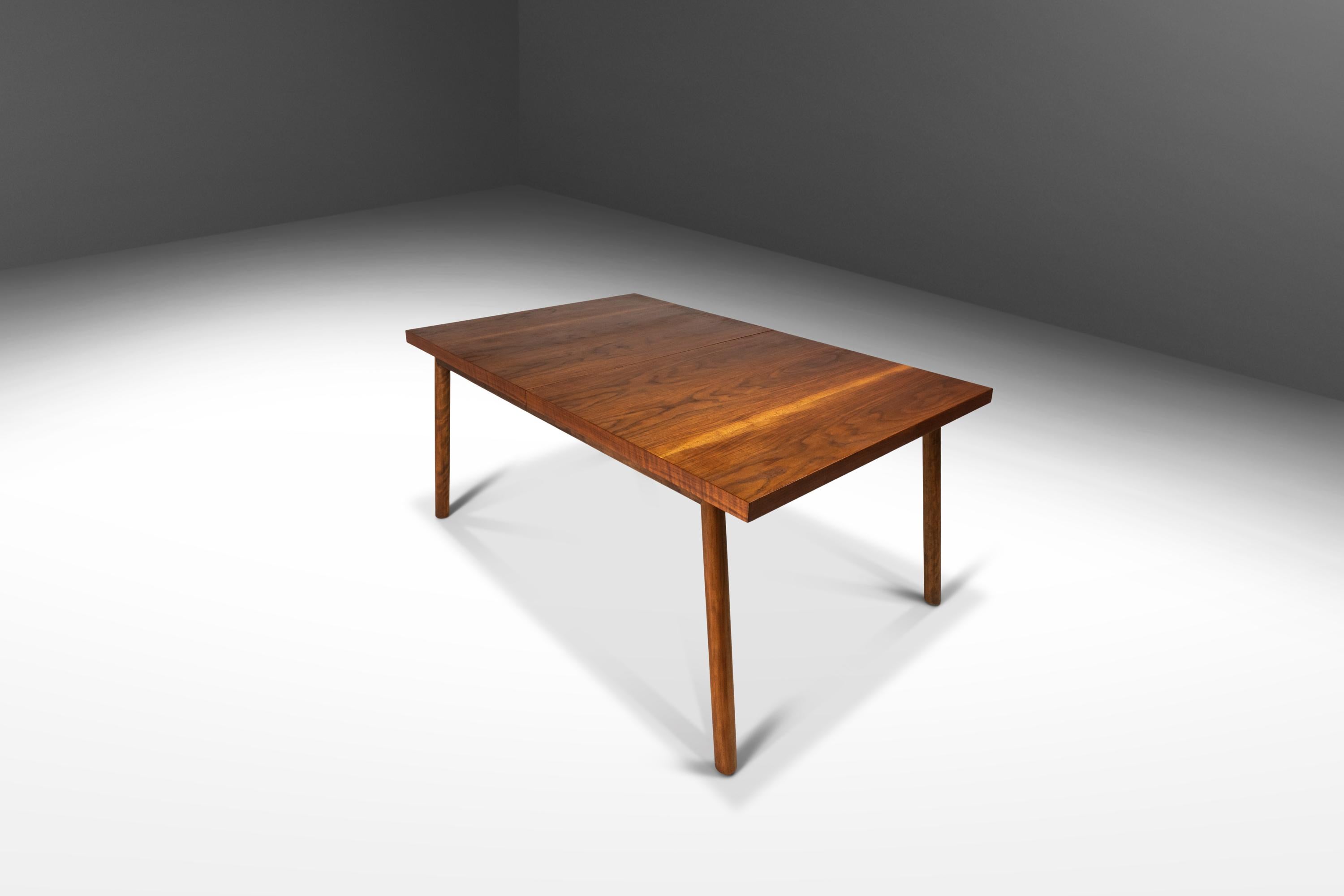 Introducing a rare expansion dining table in walnut by T.H. Robsjohn-Gibbings for Widdicomb, crafted in the 1950s in Grand Rapids, Michigan. This impressive table, in stunning original condition, is constructed from a mix of solid and veneered