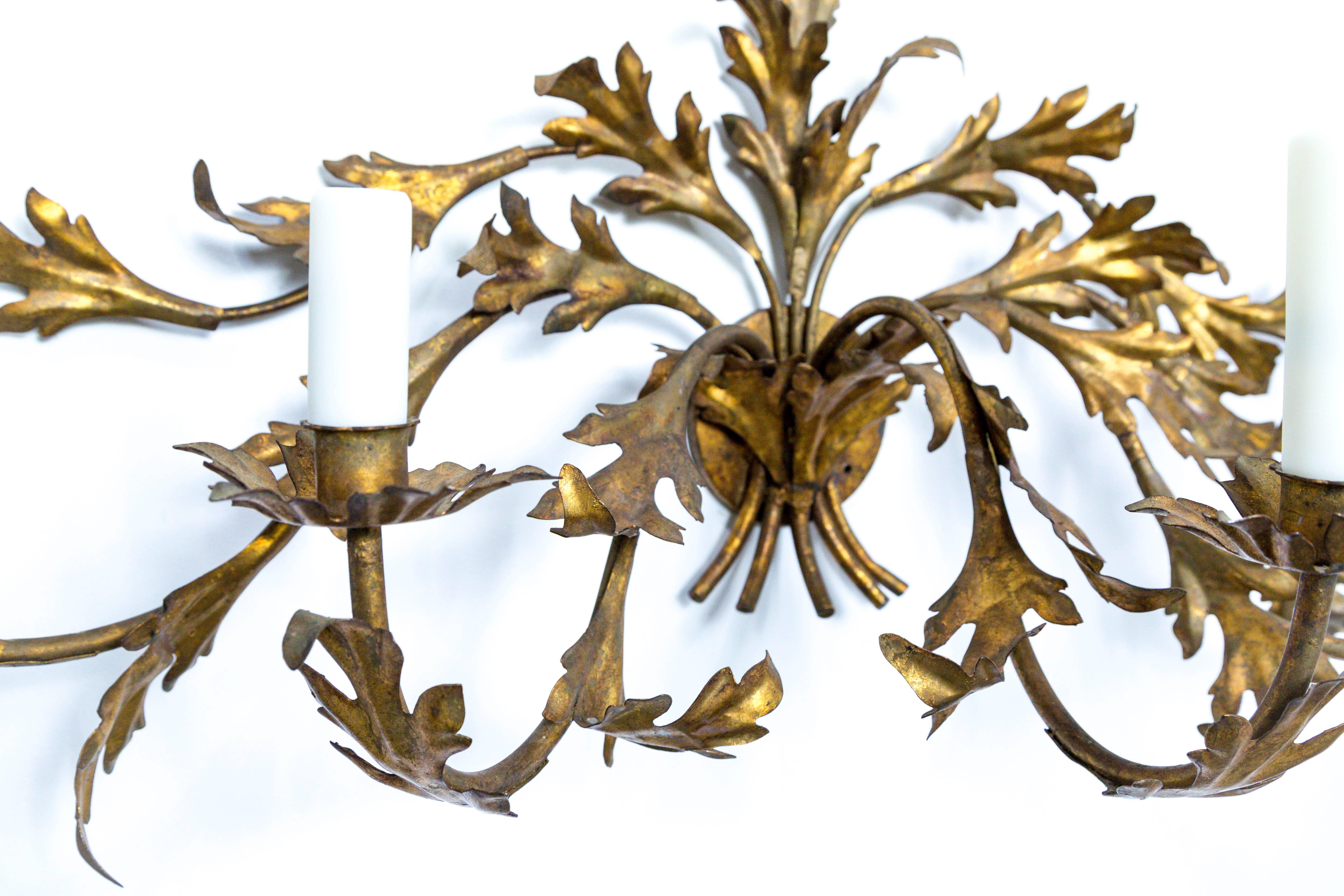 Dieser vergoldete Wandleuchter aus der Mitte des Jahrhunderts im Hollywood-Regency-Stil hat eine schöne, ausladende Form mit geschwungenen Blättern. Die Patina hat ein gealtertes Aussehen. 5 Kandelaber; neue Kerzenabdeckungen aus Polyresin. Maße: