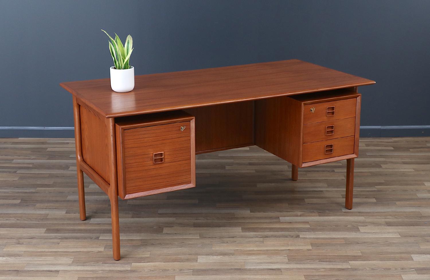 Elegant modern executive desk designed by Erik Brouer  for Brouer Møbelfabrik in Denmark circa 1950s. This striking design features a teak wood frame with three spacious drawers on its fight side and a large filing drawer on its left side. Its best
