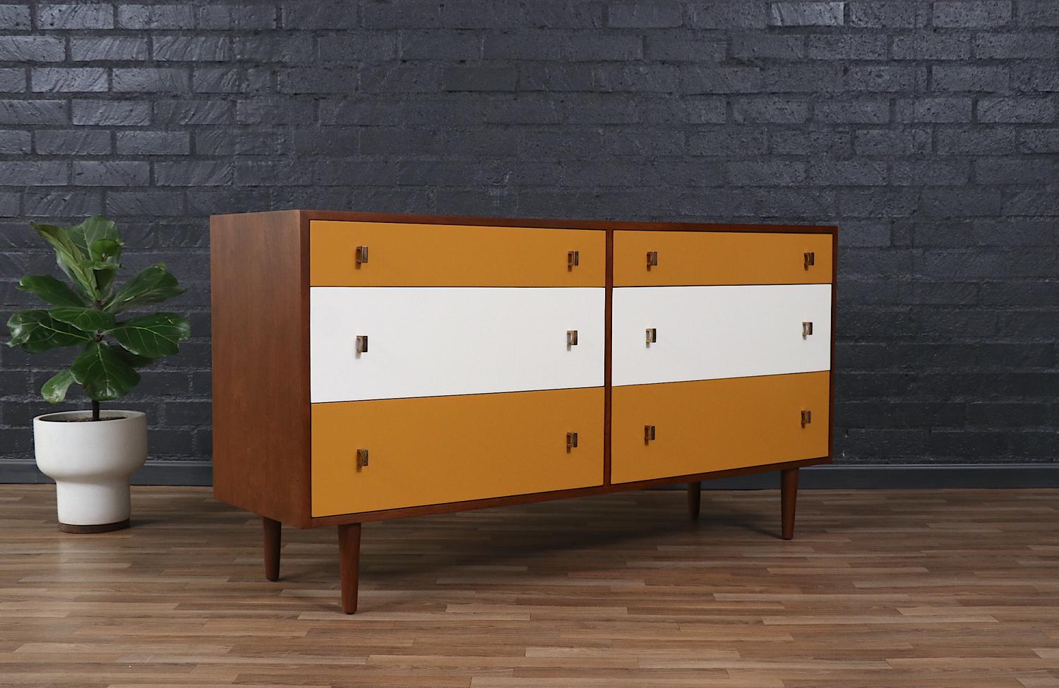 Questo sorprendente cassettone Mid-Century Modern di Glenn of California presenta un'elegante miscela di forma e funzionalità. La struttura in noce appena rifinita è completata dai frontali dei cassetti laccati satinati in un'audace combinazione di