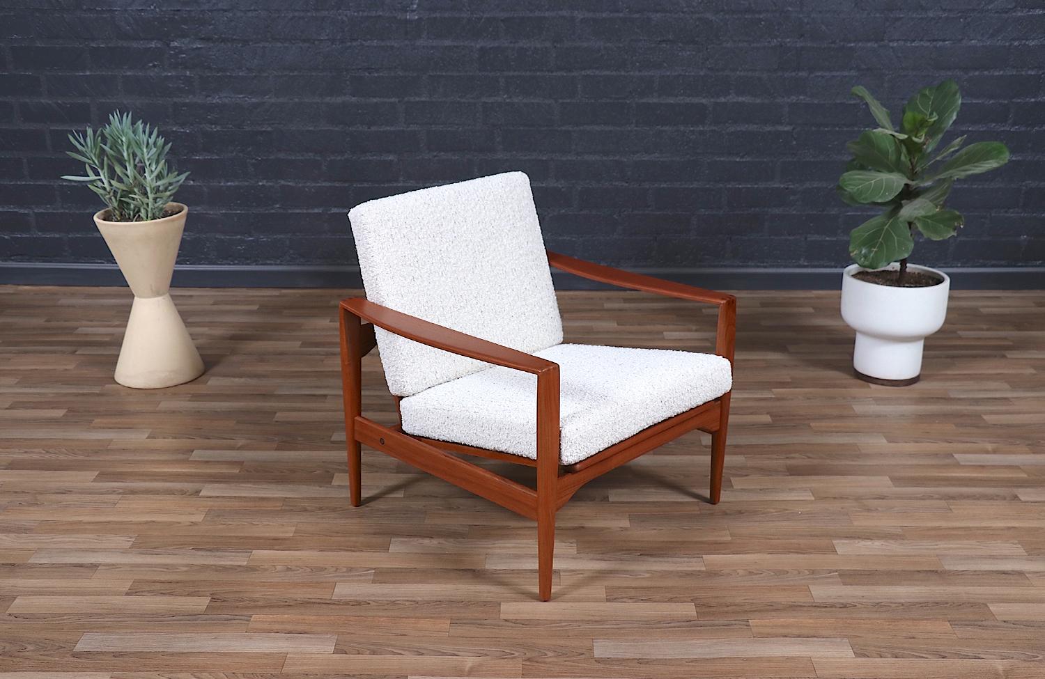 This rare Danish Modern lounge chair by Illum Wikkelsø for Niels Eilersen is a testament to the refined craftsmanship of the 1950s Scandinavian design movement. The solid teak wood frame, newly refinished to highlight its warm tones and exquisite