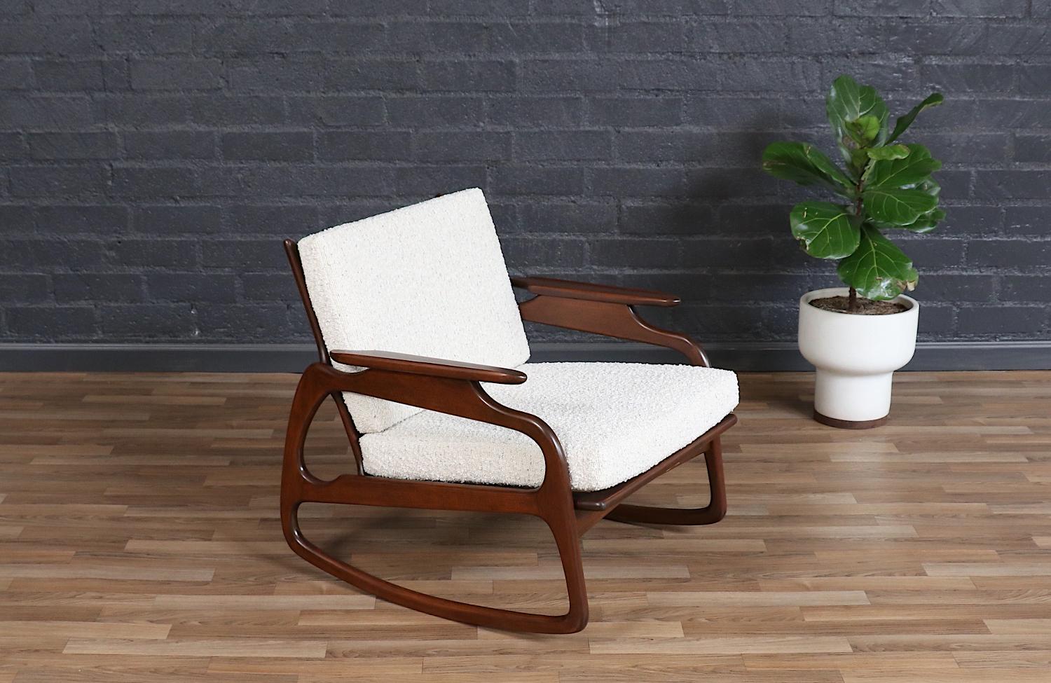 A striking example of Italian mid-century design, this elegant rocking chair from the 1960s boasts a sculptural walnut-stained beechwood frame with graceful curves and an airy presence. The backrest features its original cane panel, lending a warm