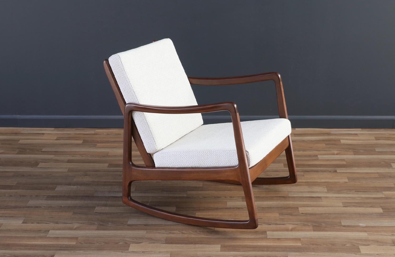 Enhance your home with the timeless elegance of the Ole Wanscher Model FD-120 Rocking Chair, crafted by France & Son in the 1950s. Made from walnut-stained beechwood, this chair features new tweed fabric, high-density foam, and springs for ultimate