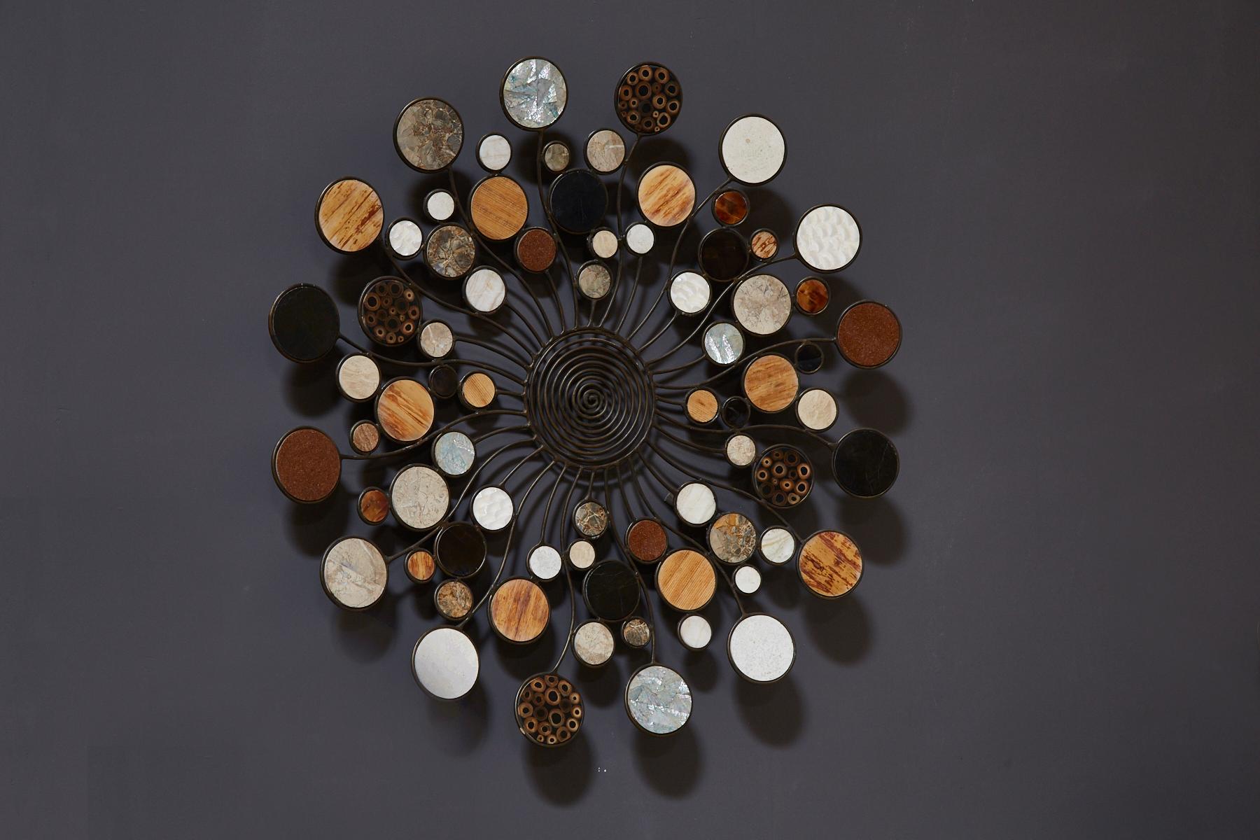 Round wall sculpture with blackened metal structure emanating from a central circle. Each circle hand-inlaid with natural materials such as stone, seashell and natural fibers.

All furnishings are made from 100% natural Fossil Stone or Seashell