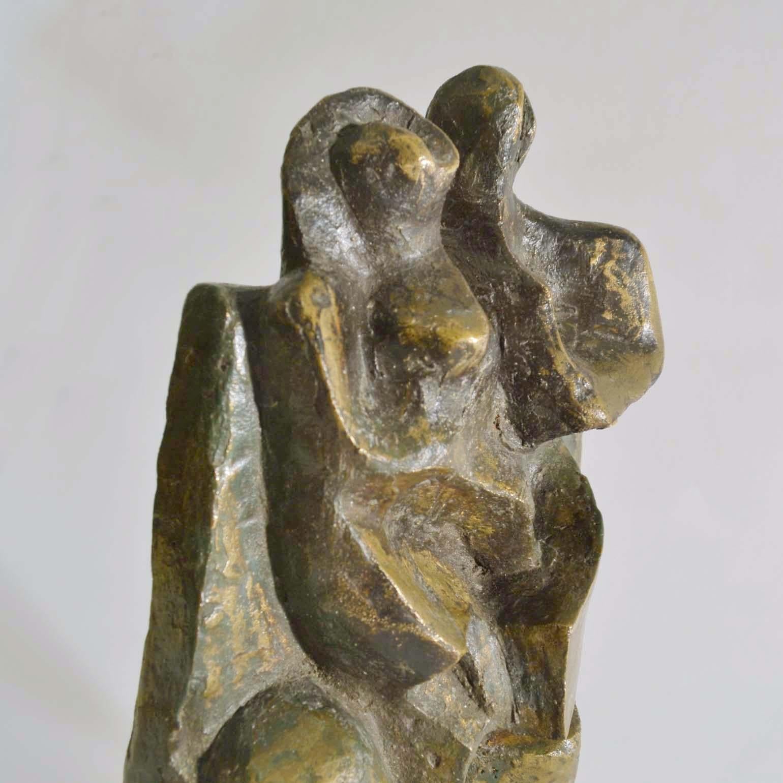 Sculpture expressionniste en bronze représentant un couple debout avec un enfant encadré par un mur rectangulaire. La composition de la toile de fond se poursuit dans la base et sert de cadre à la composition. La sculpture, avec sa patine et ses